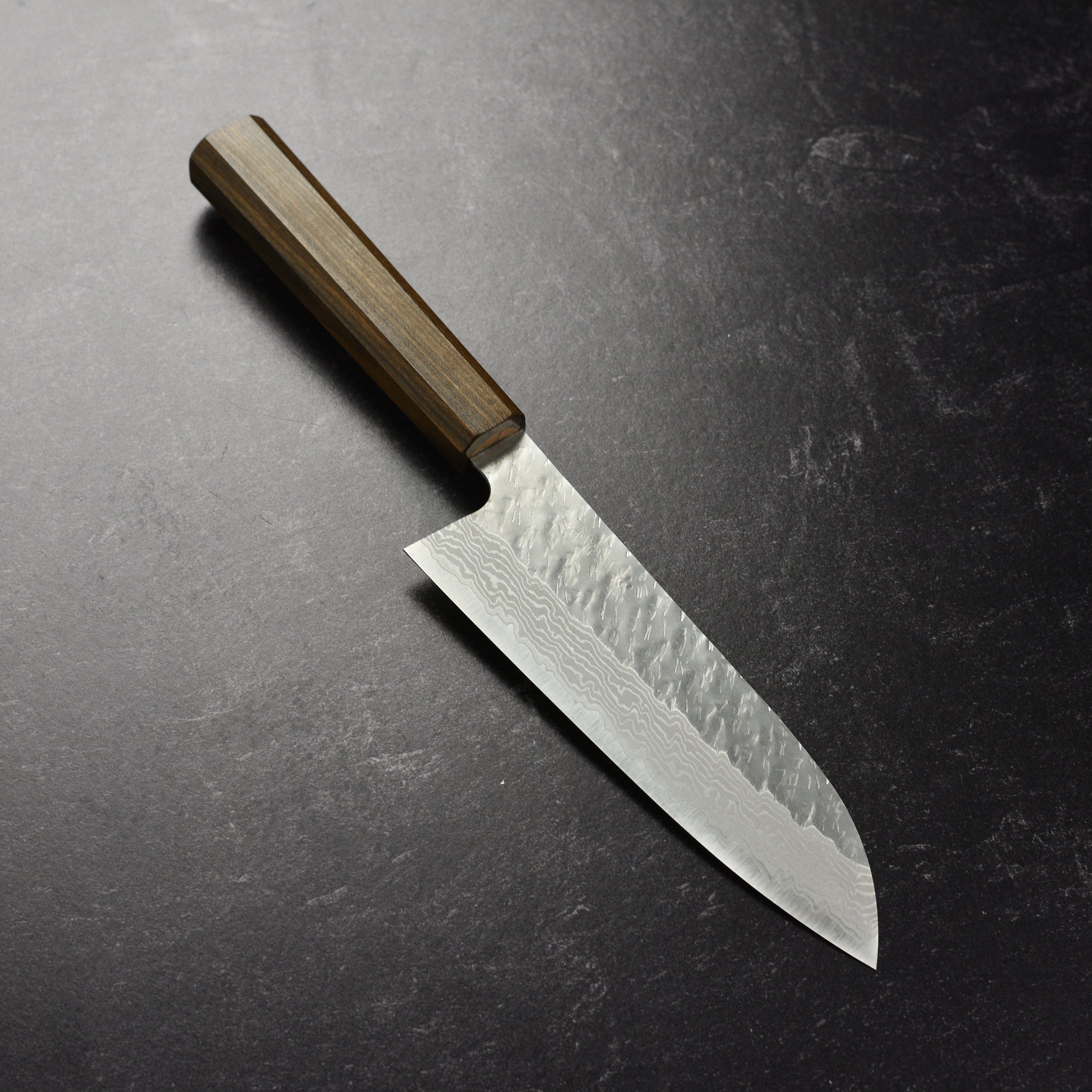 Nigara VG10 Santoku knife on a cutting board, highlighting its sharpness and design.