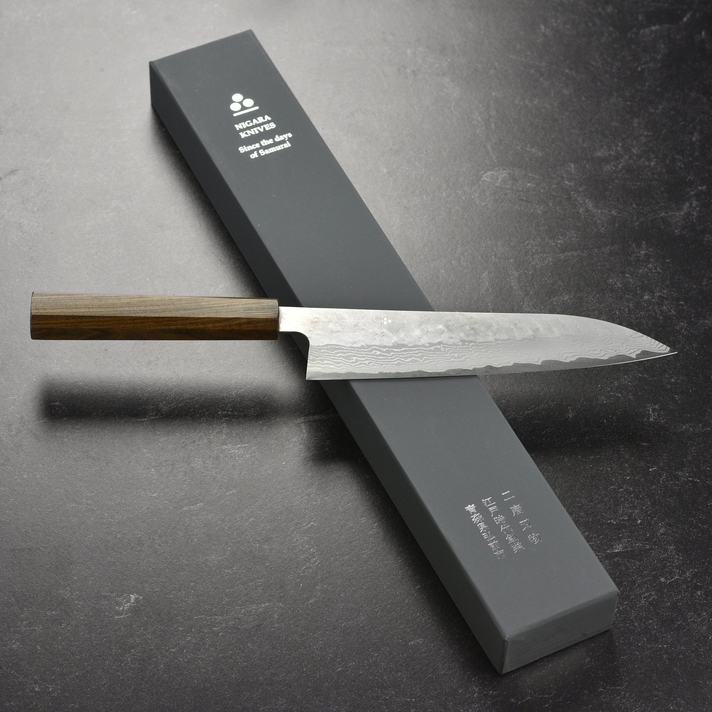 Tsuchime Damascus Gyuto Knife displayed on a cutting board with fresh ingredients
