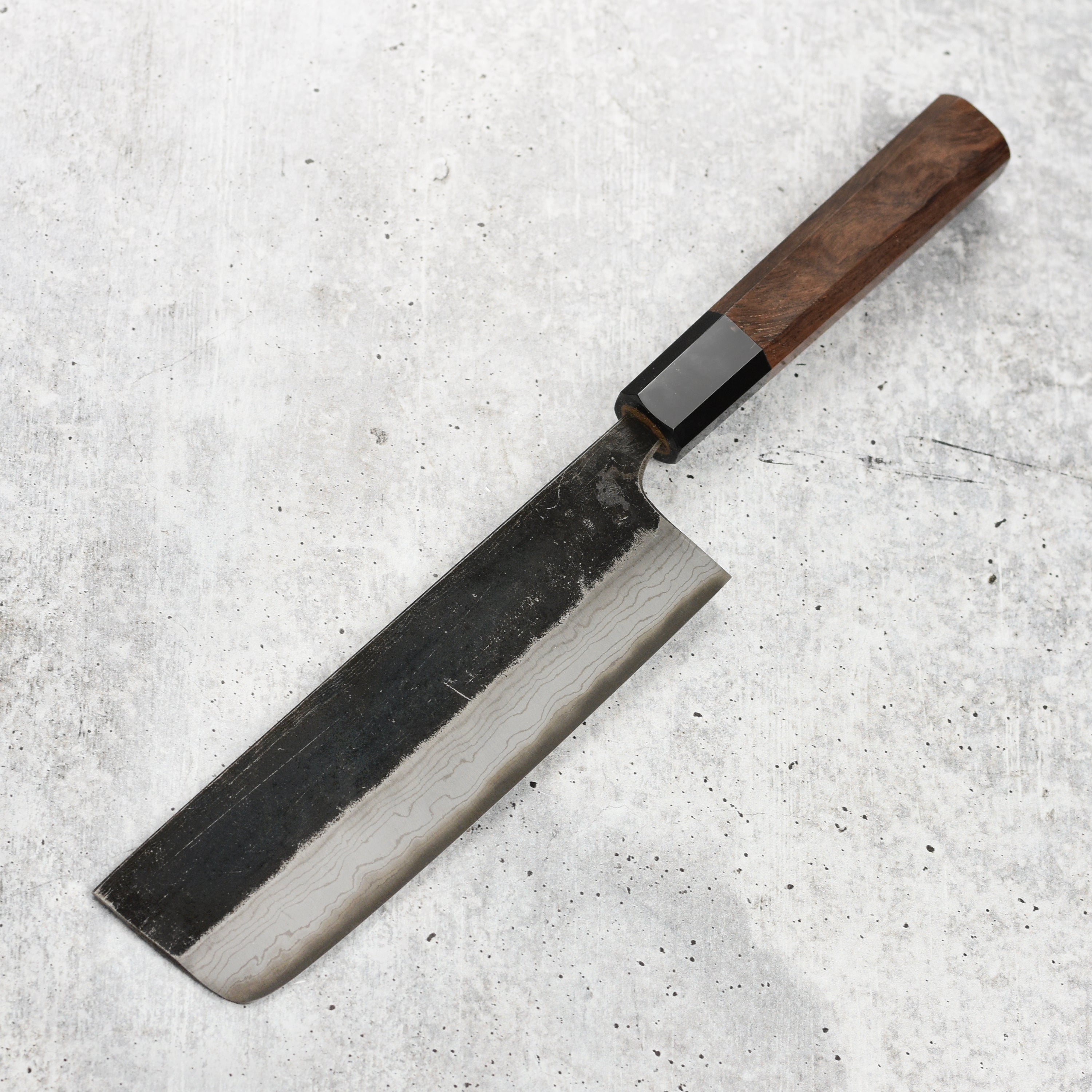Japanese Nakiri knife in hand, highlighting kurouchi finish and blade details
