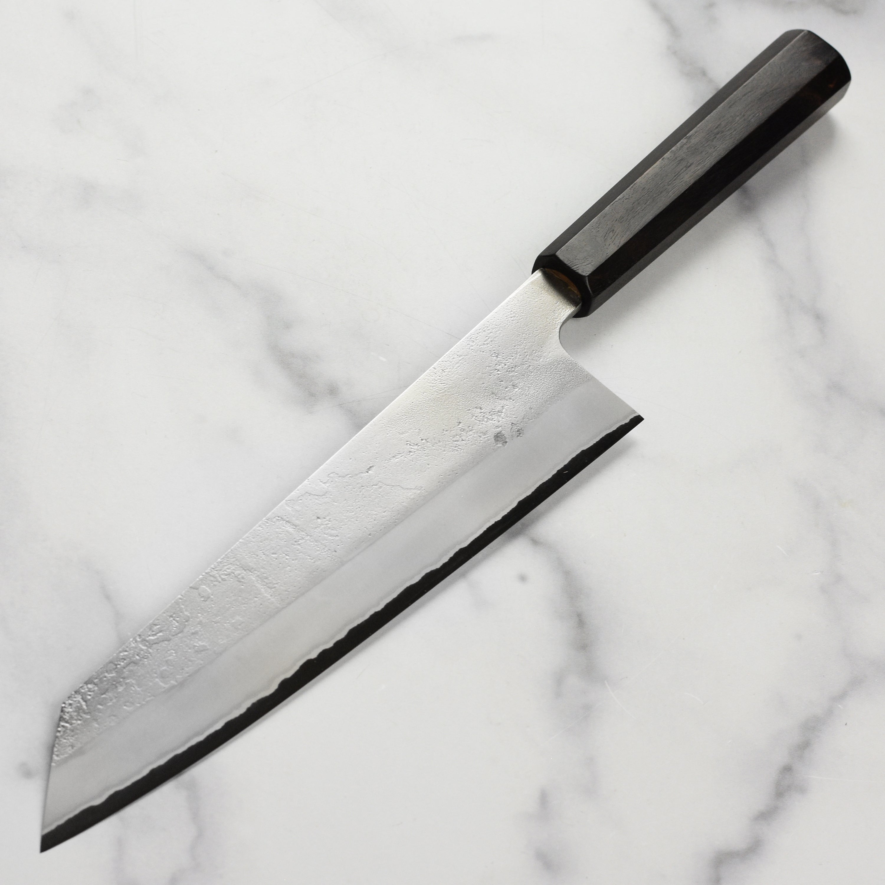 Close-up of the Yoshikane Shirogami chef knife in use, demonstrating precision slicing.