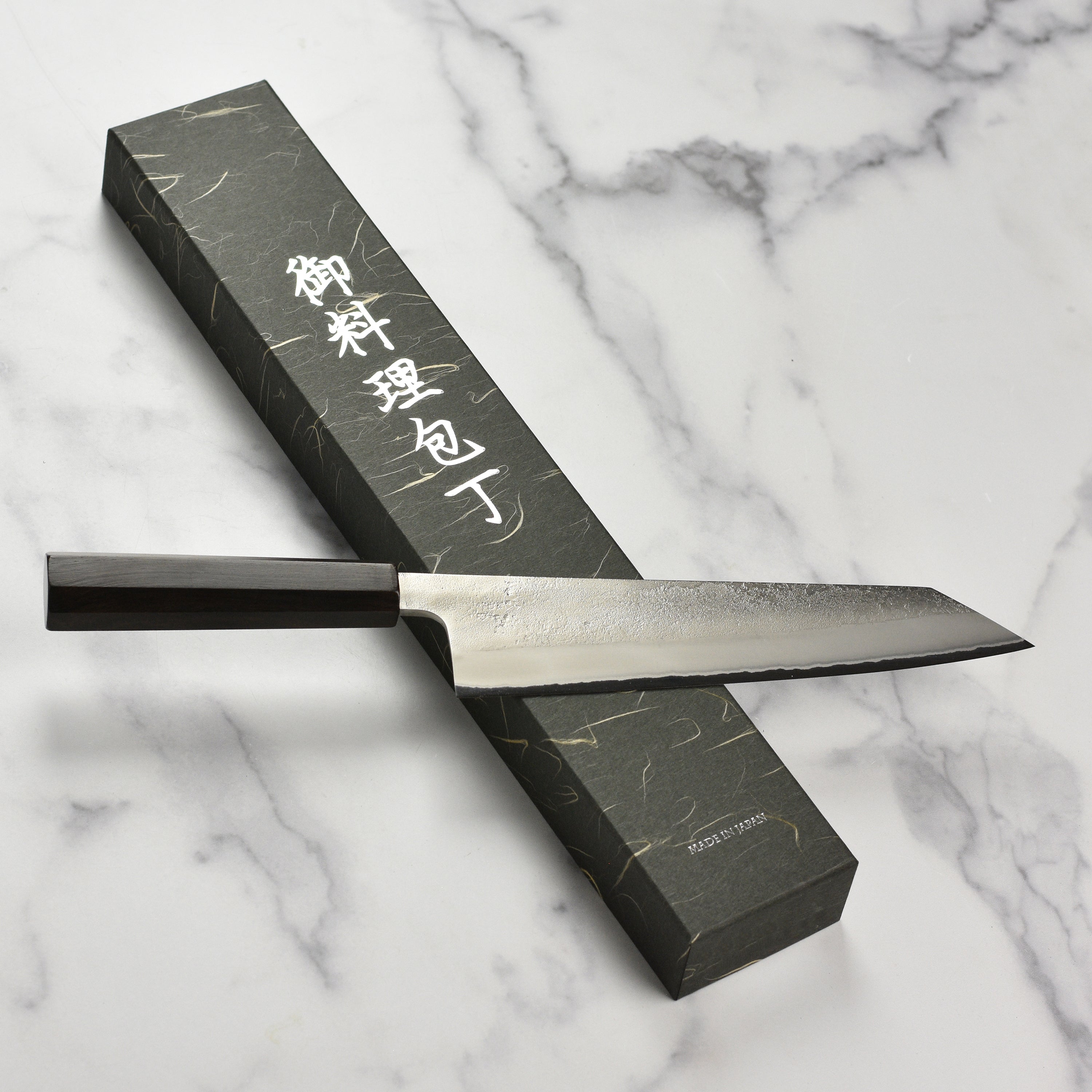 Yoshikane Shirogami knife displayed on a wooden cutting board with fresh ingredients.