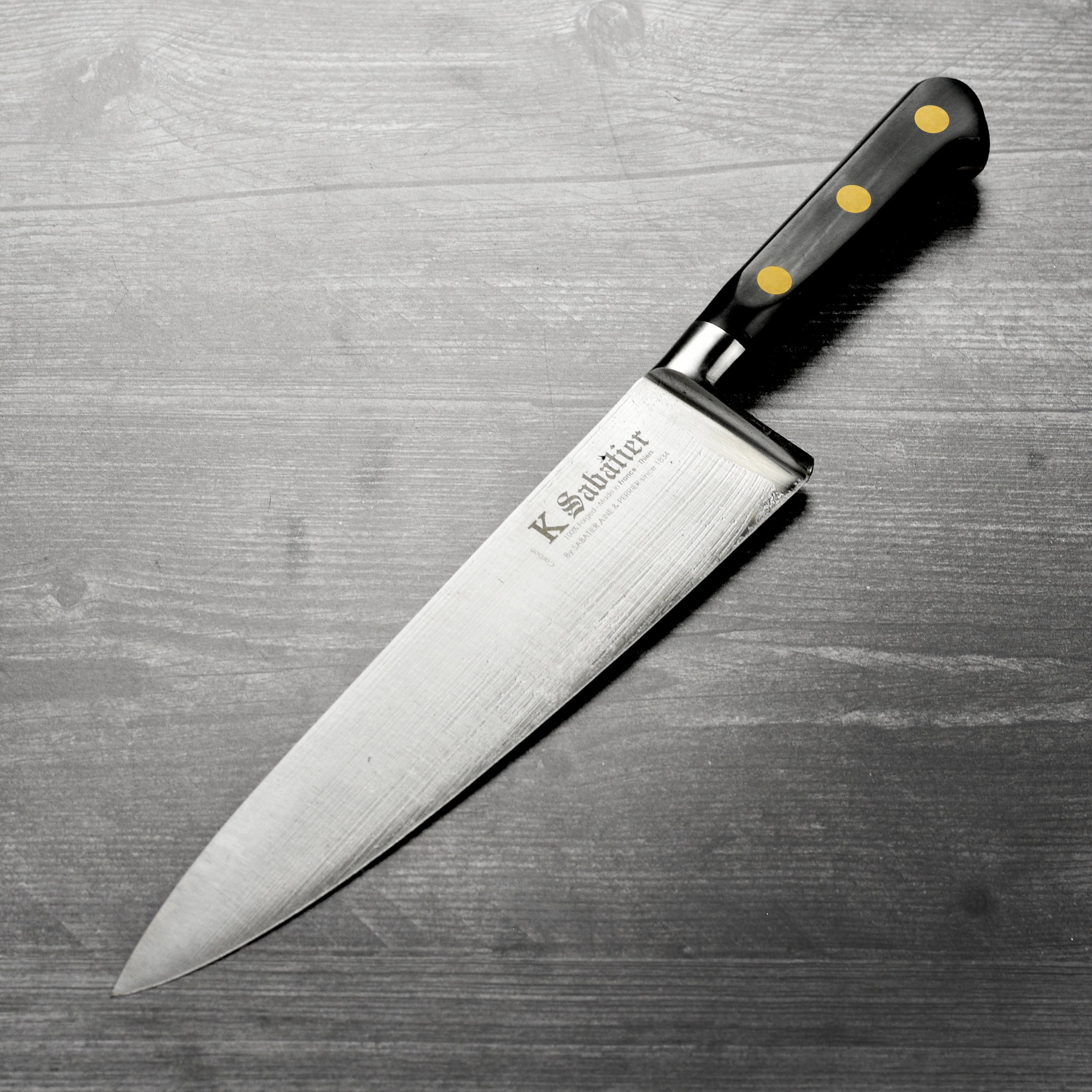 Close-up of K Sabatier 9 inch chefs knife with carbon steel blade and brass rivets