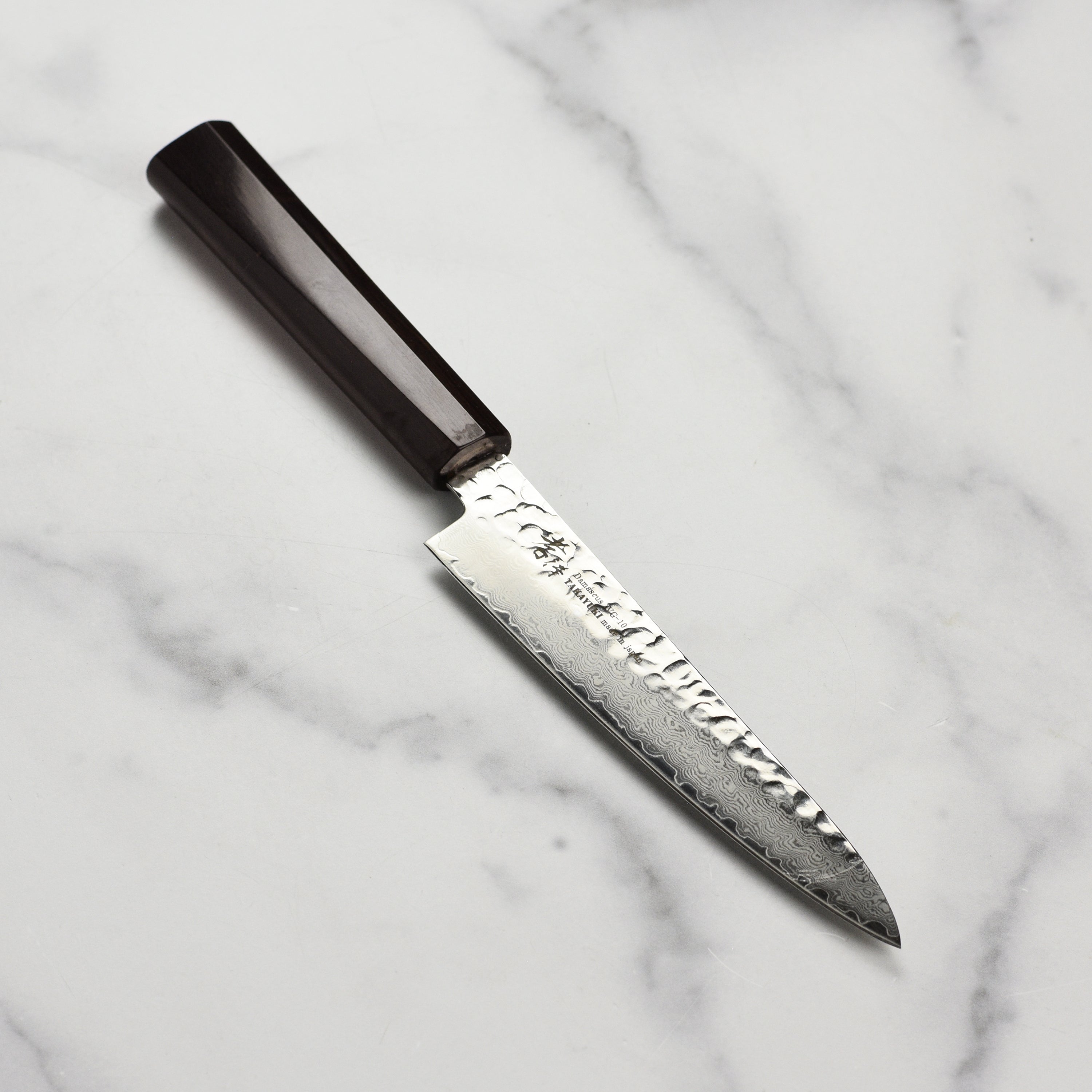 Close-up of Takayuki Tsuchime Damascus petty knife highlighting the blade and ebony handle.