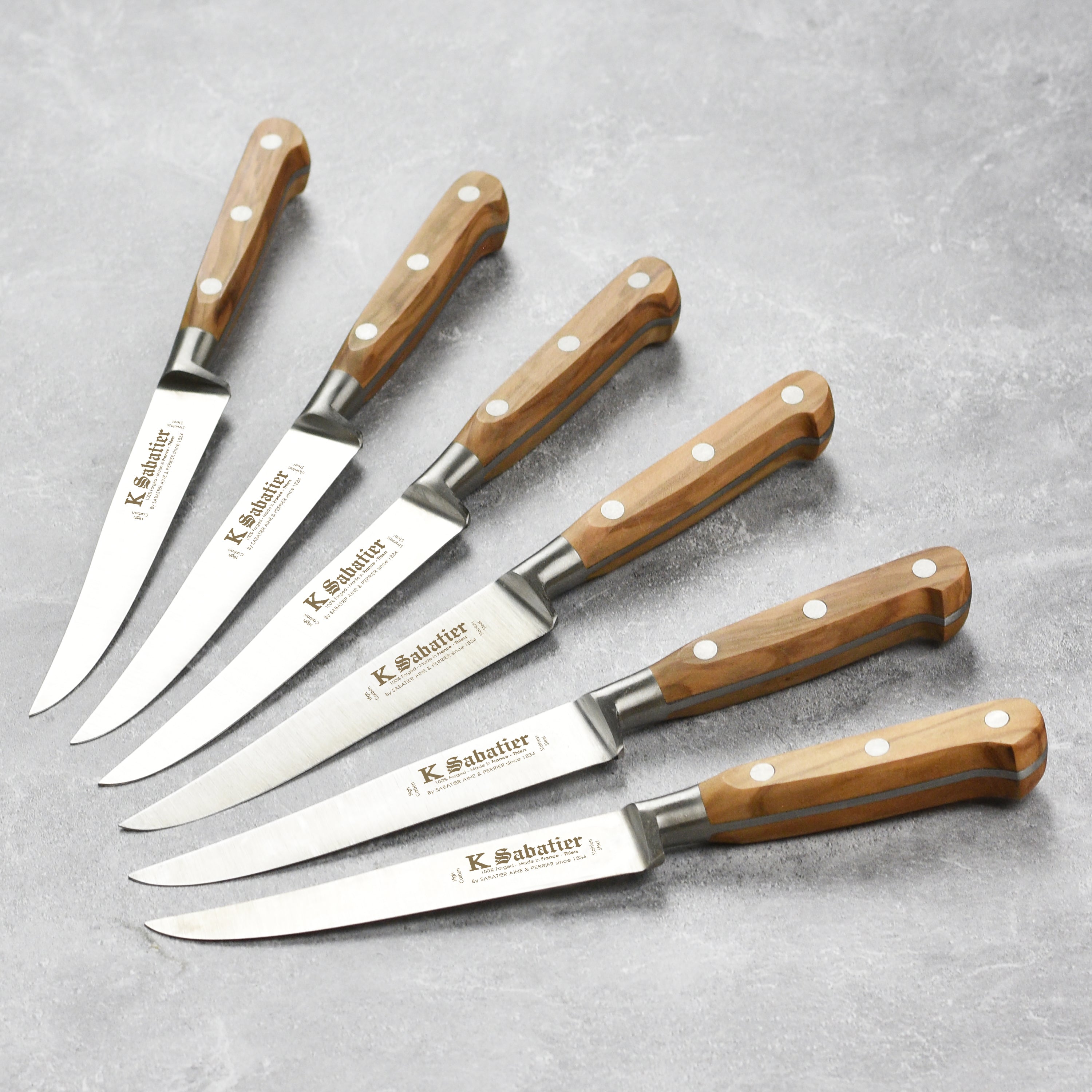 Close-up of olive wood steak knives with stainless steel rivets for elegant kitchen cutlery