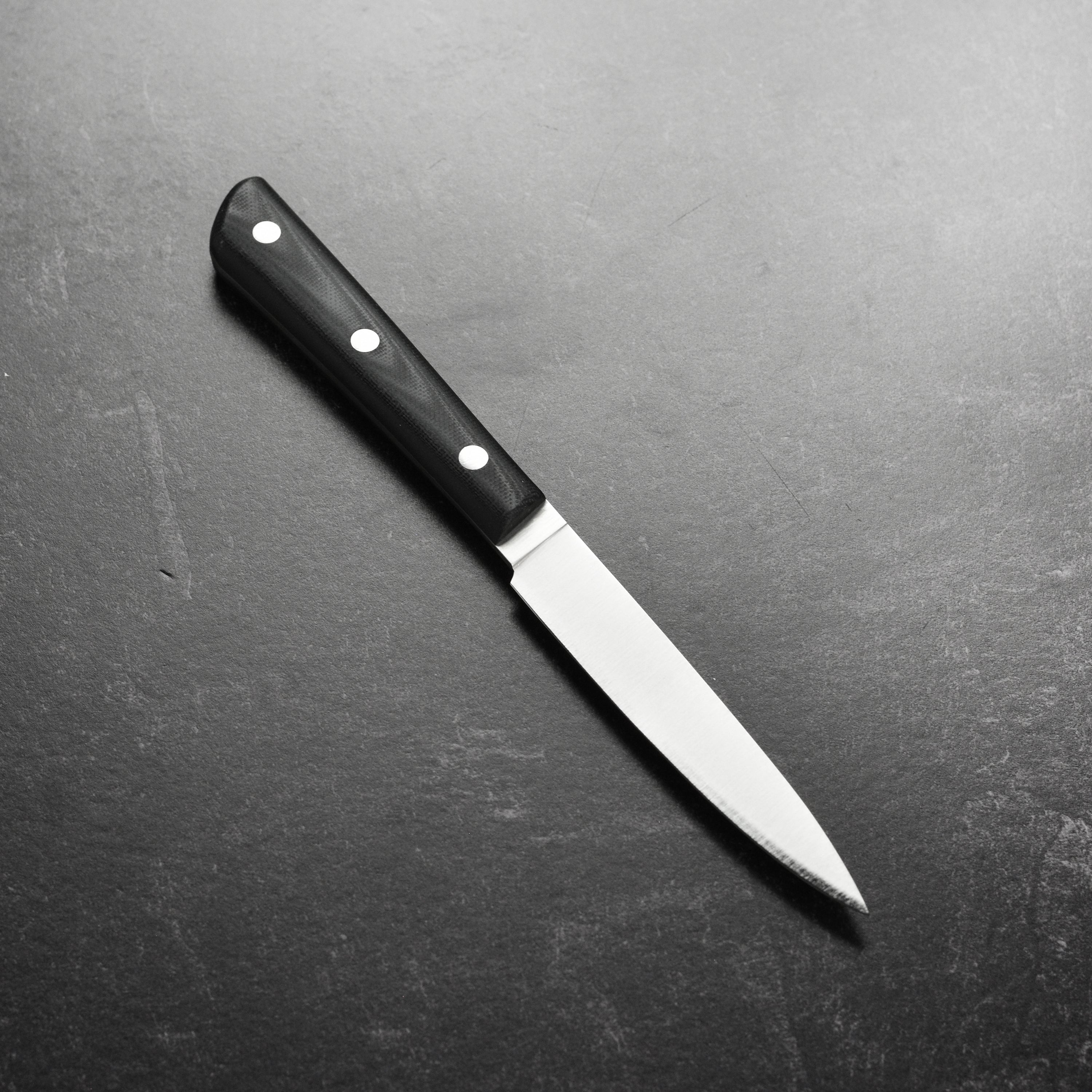 Detailed view of the 4-inch paring knife with G10 handle and polished edge