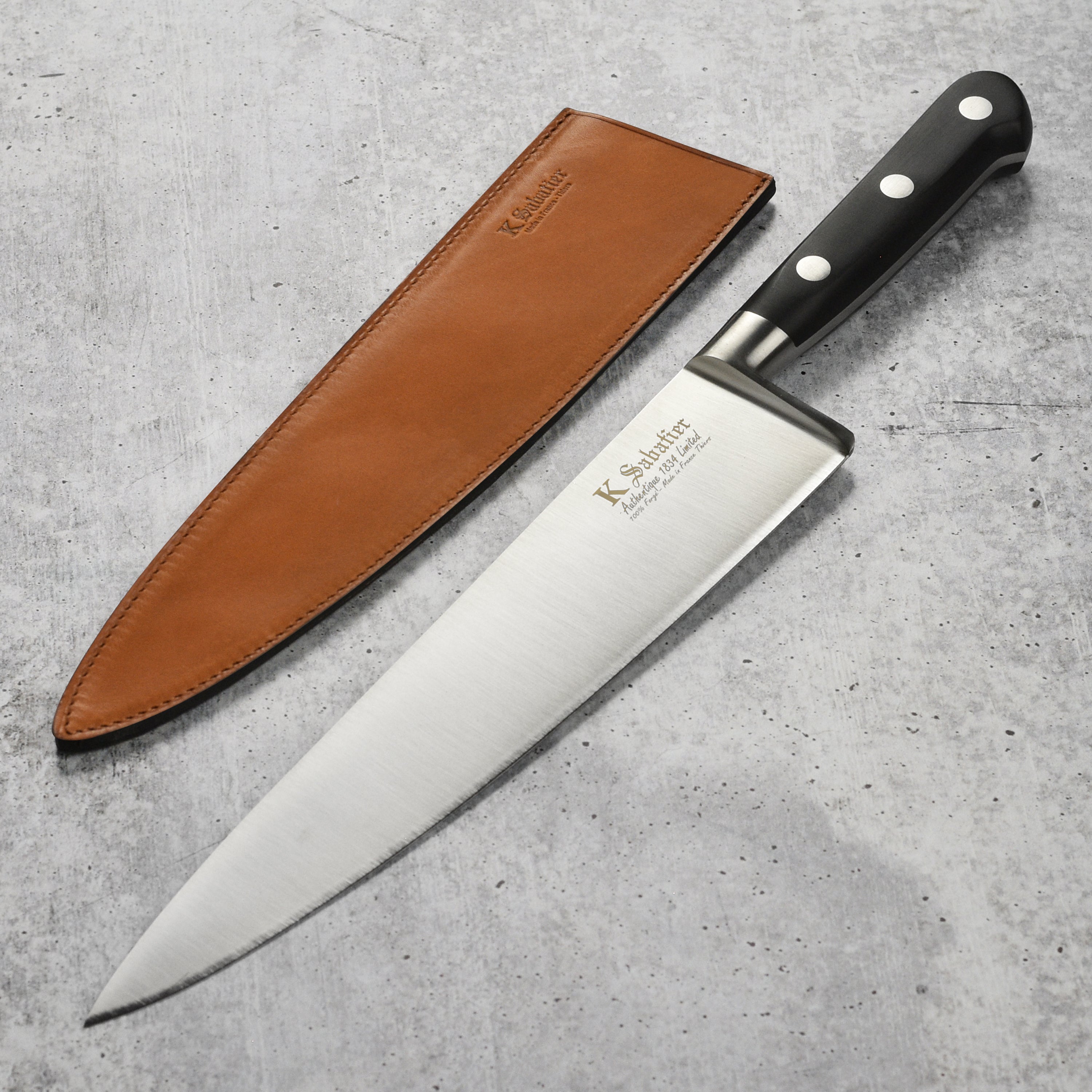 Overhead view of premium handcrafted chef's knife with brown leather sheath beside fresh ingredients