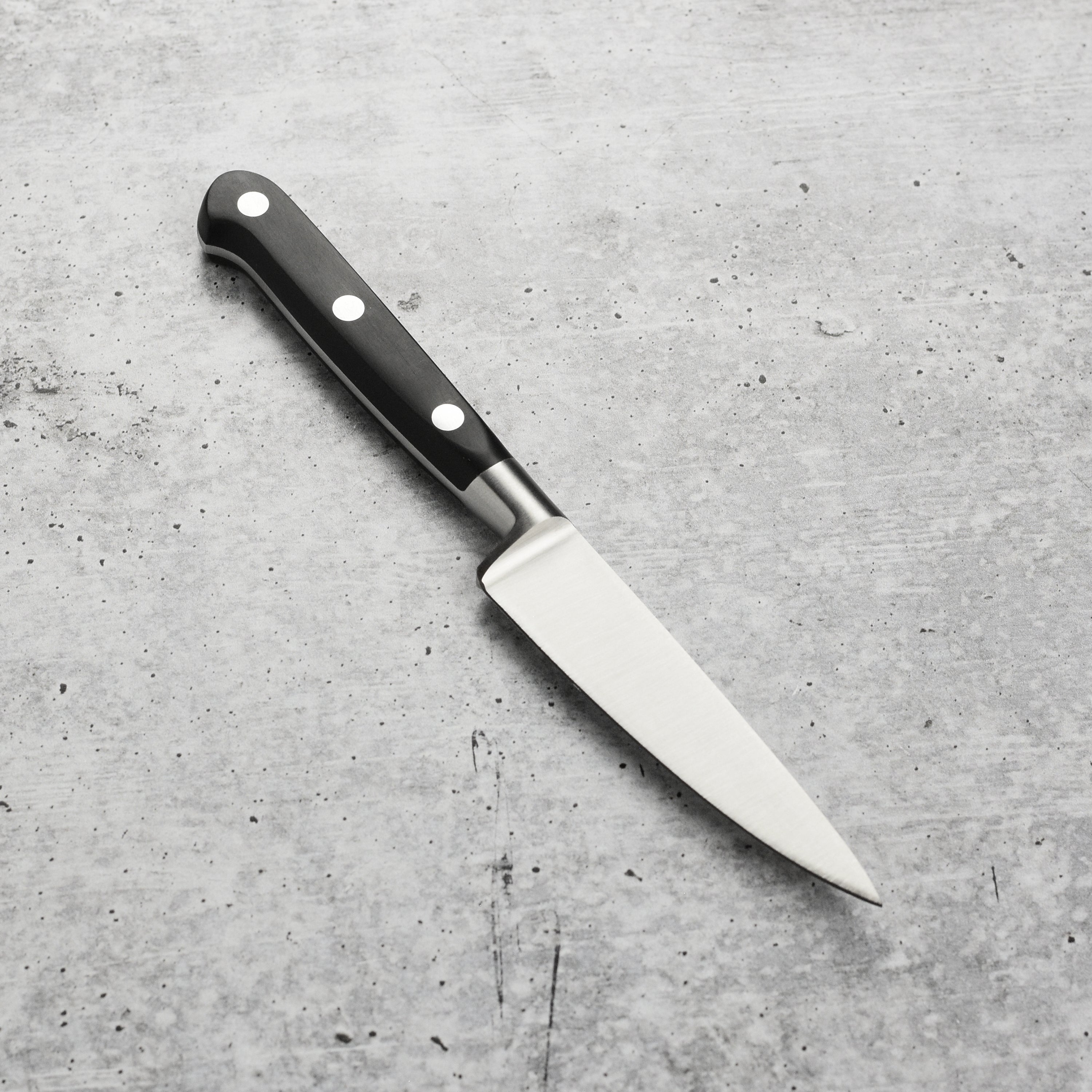 Elegant display of K Sabatier 4" paring knife with brown leather sheath on a rustic kitchen countertop.