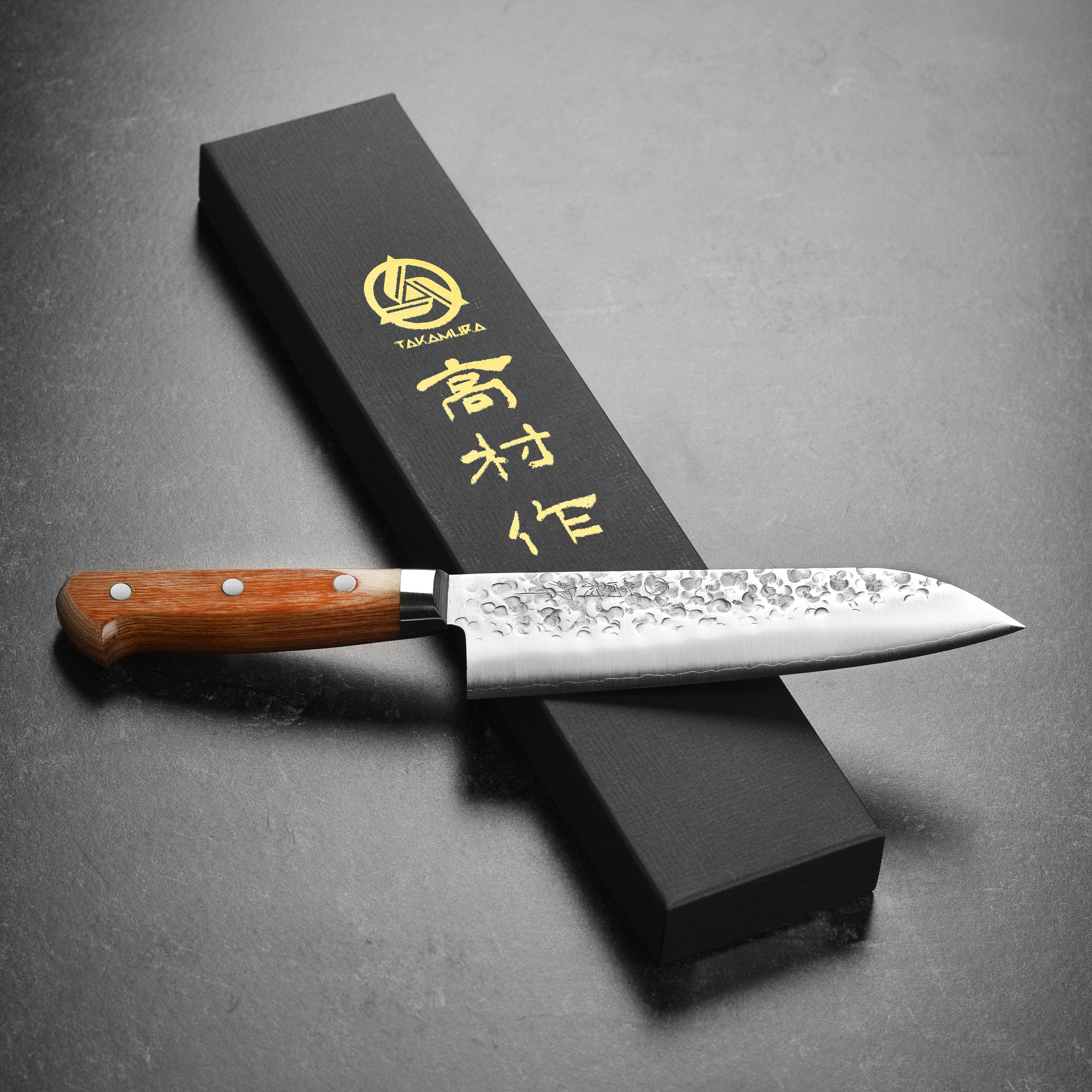 Chef slicing vegetables with Takamura Chromax Tsuchime Santoku in a modern kitchen setting