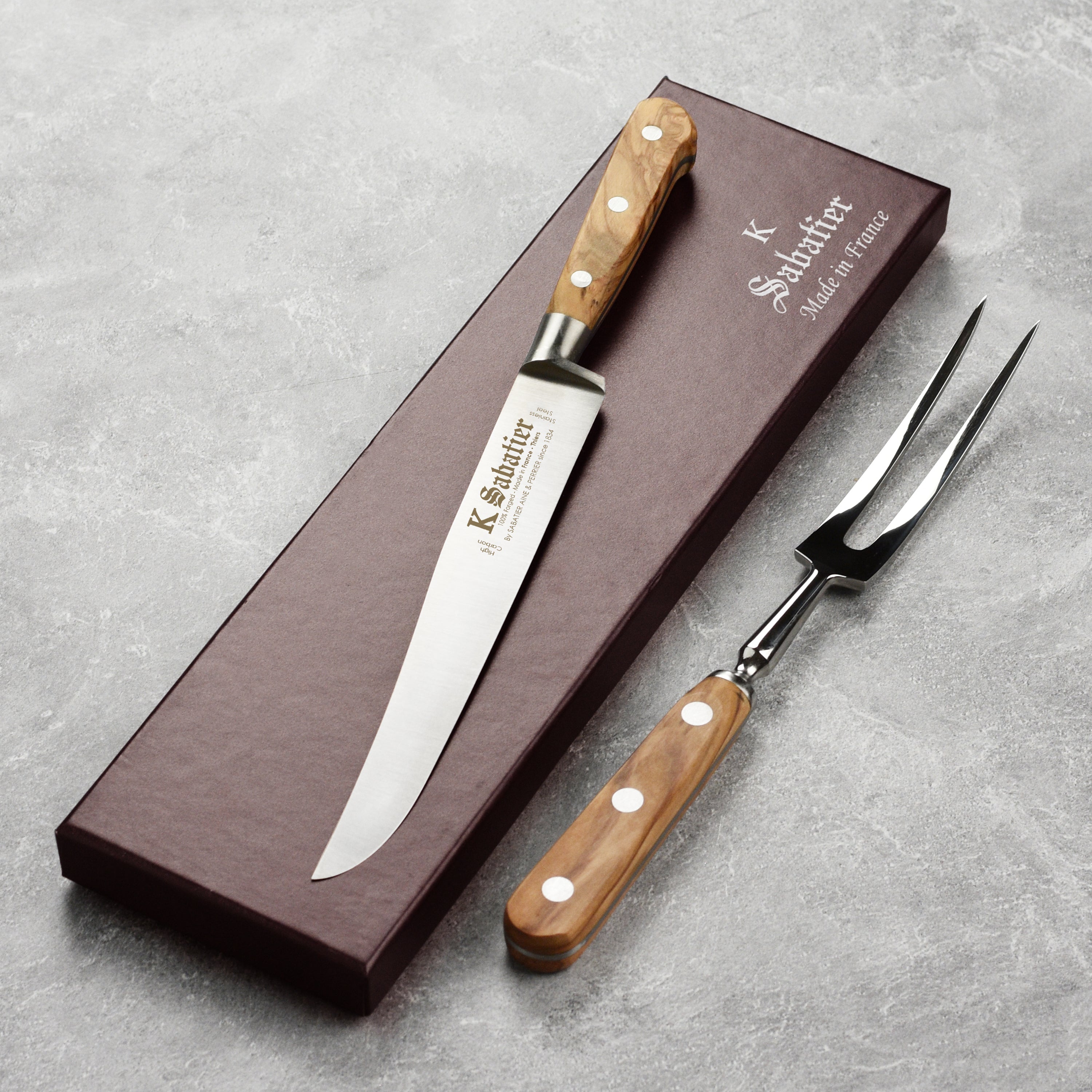 Side view of the olive wood carving knife and fork set elegantly displayed on a wooden cutting board.