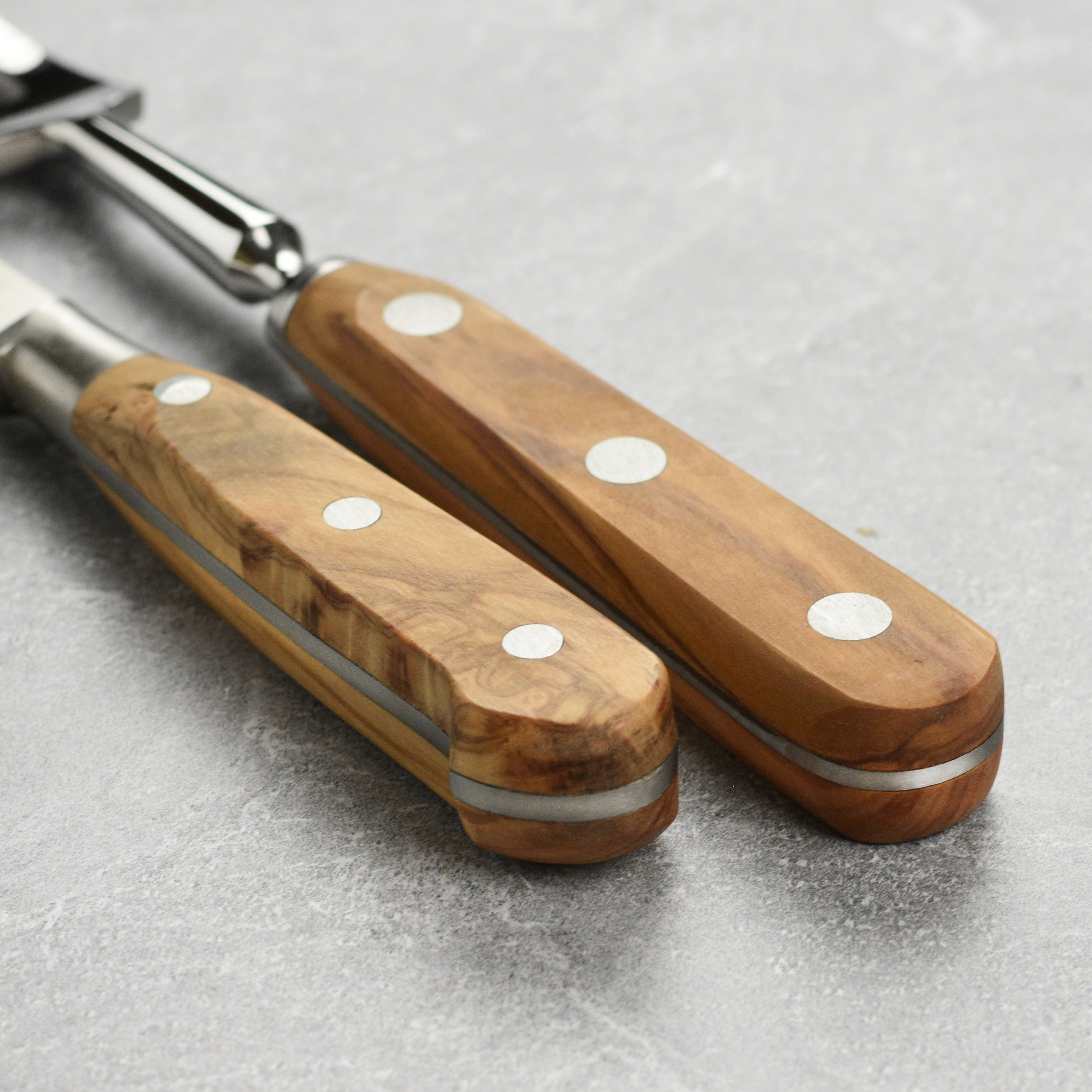 Side view of the olive wood carving knife and fork set elegantly displayed on a wooden cutting board.
