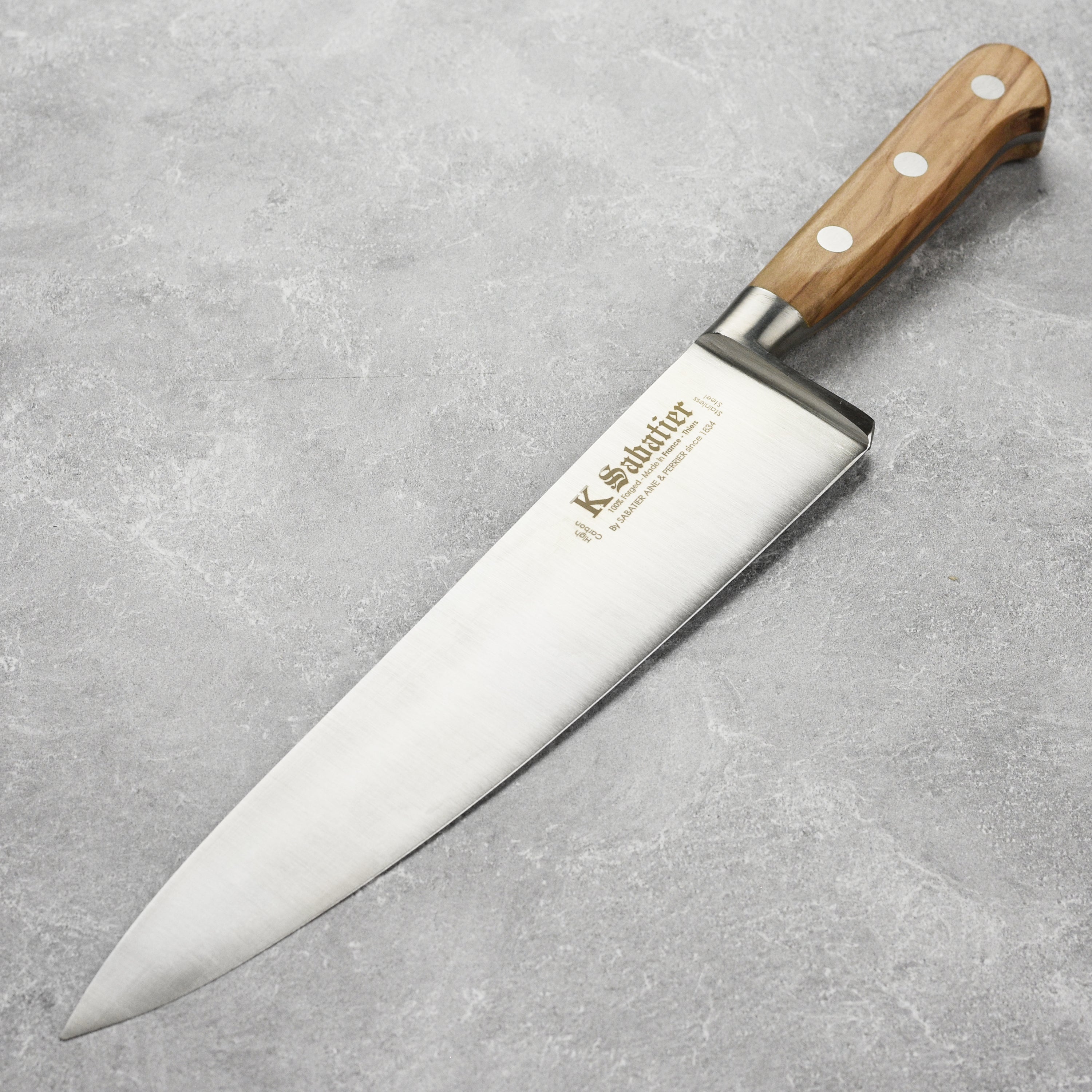 Overhead view of Sabatier olive wood chef's knife on rustic cutting board