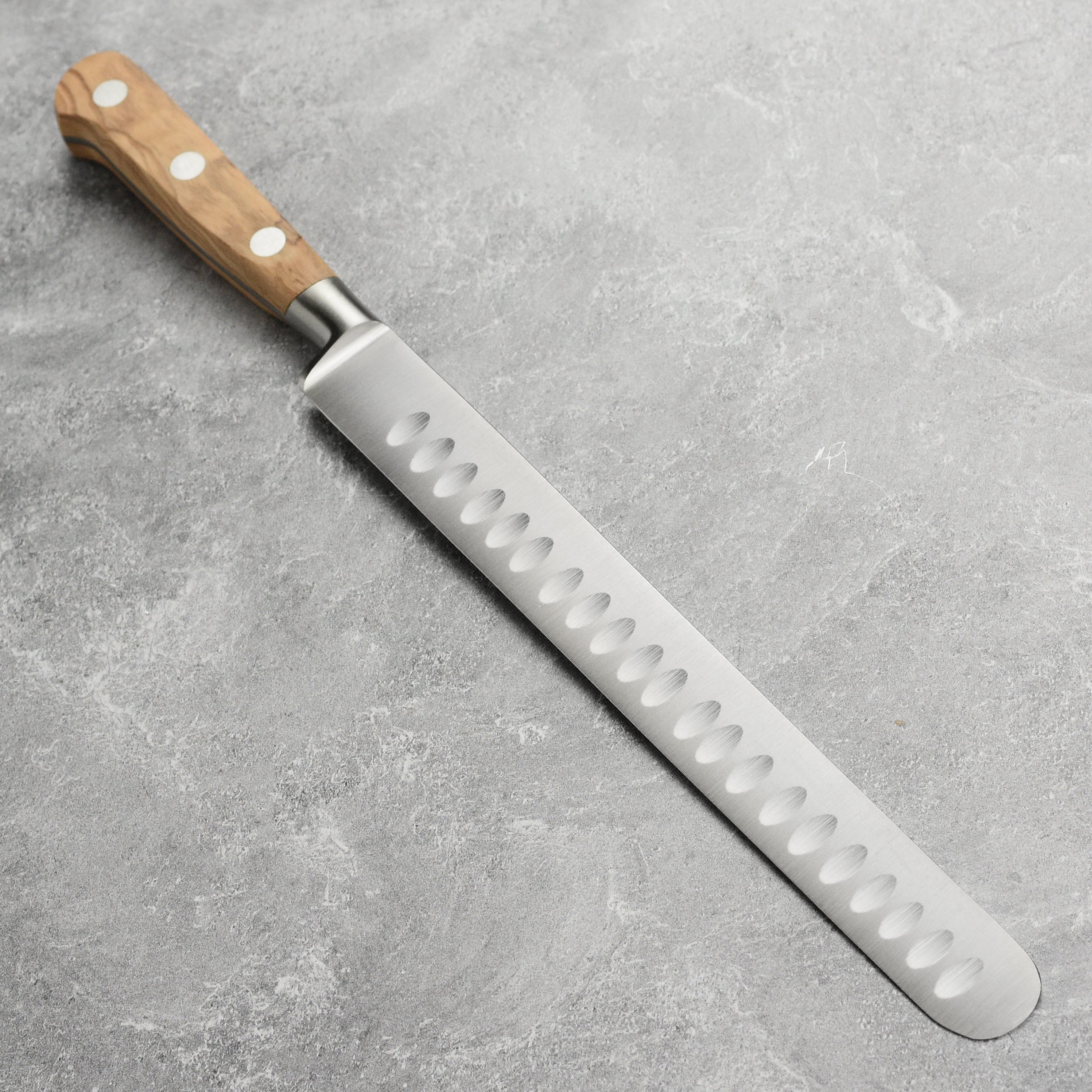 Close-up of the hollow edge on the K Sabatier slicing knife, perfect for reducing friction while slicing.