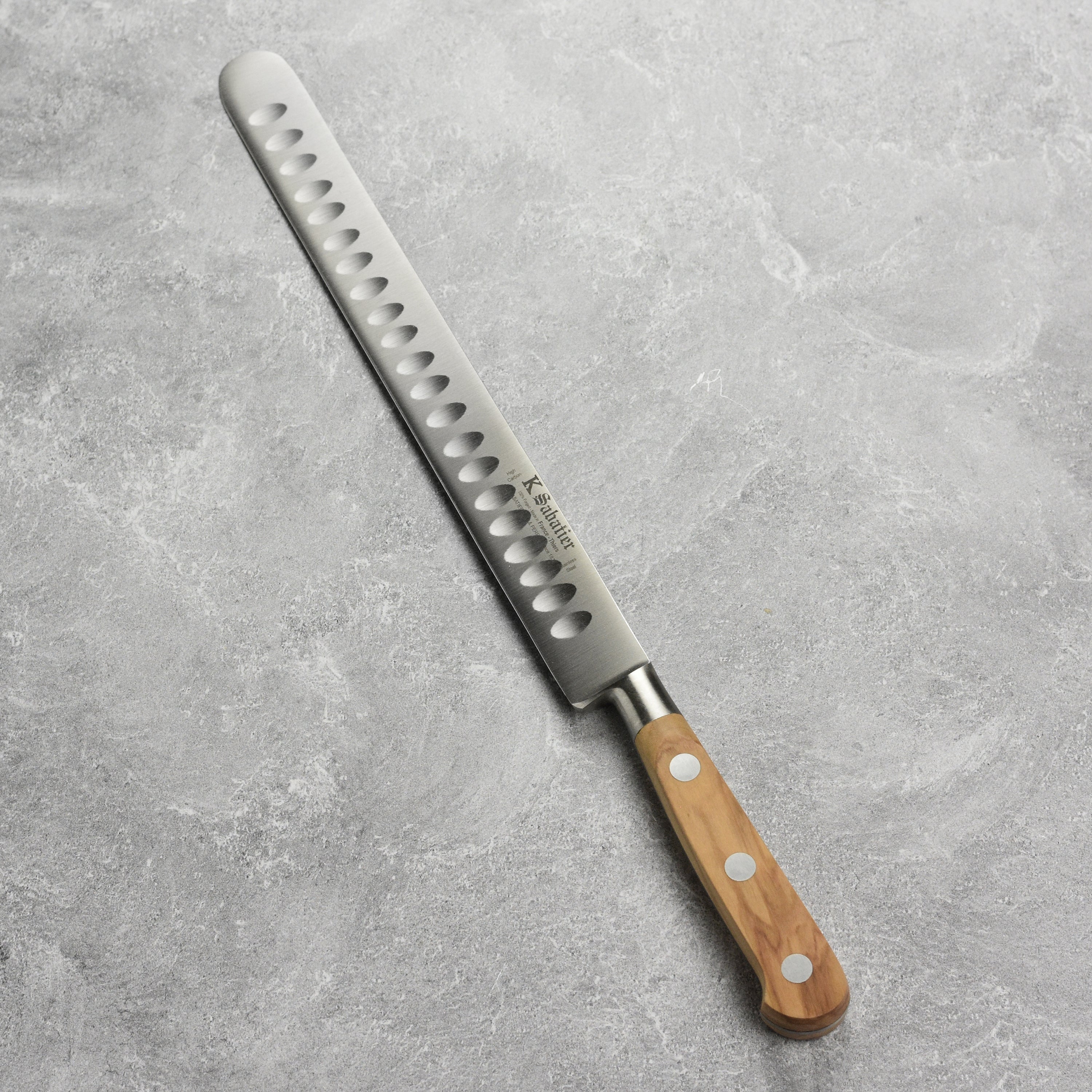 K Sabatier olive wood slicing knife displayed in a kitchen setting, demonstrating its use for cutting meats.