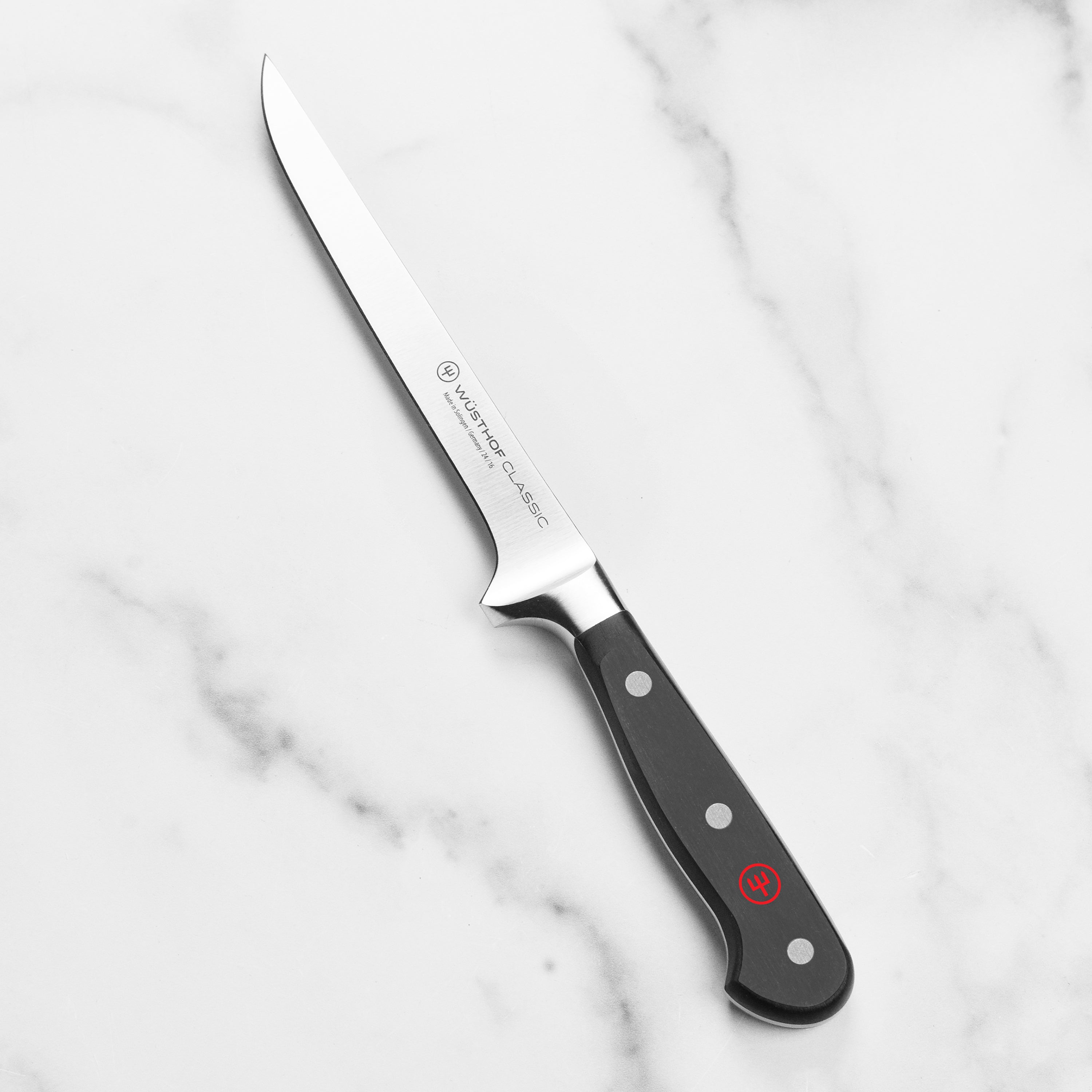 Wusthof boning knife in action, skillfully deboning meat on a cutting board.