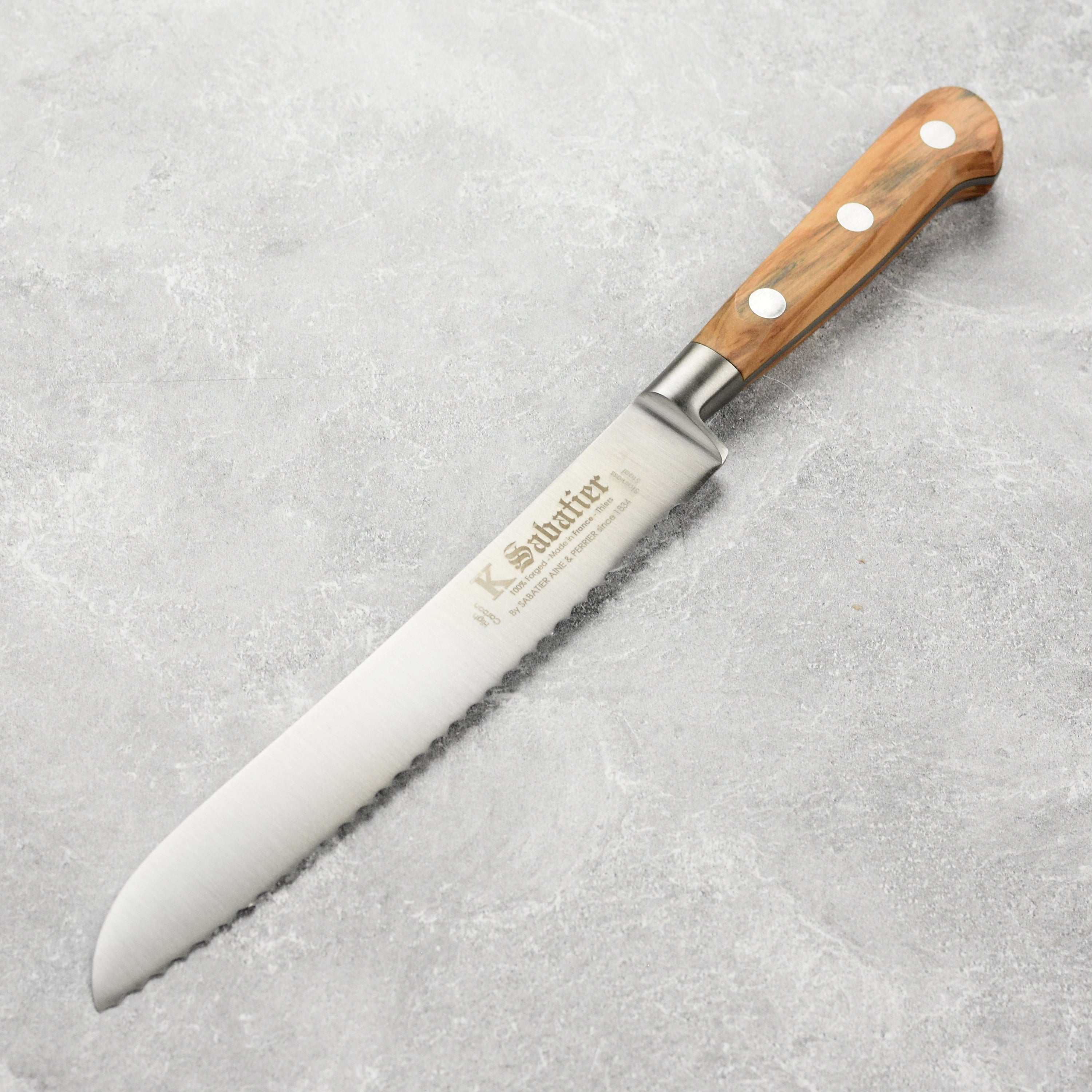 K Sabatier olive wood bread knife with a sleek stainless steel blade and comfortable handle.