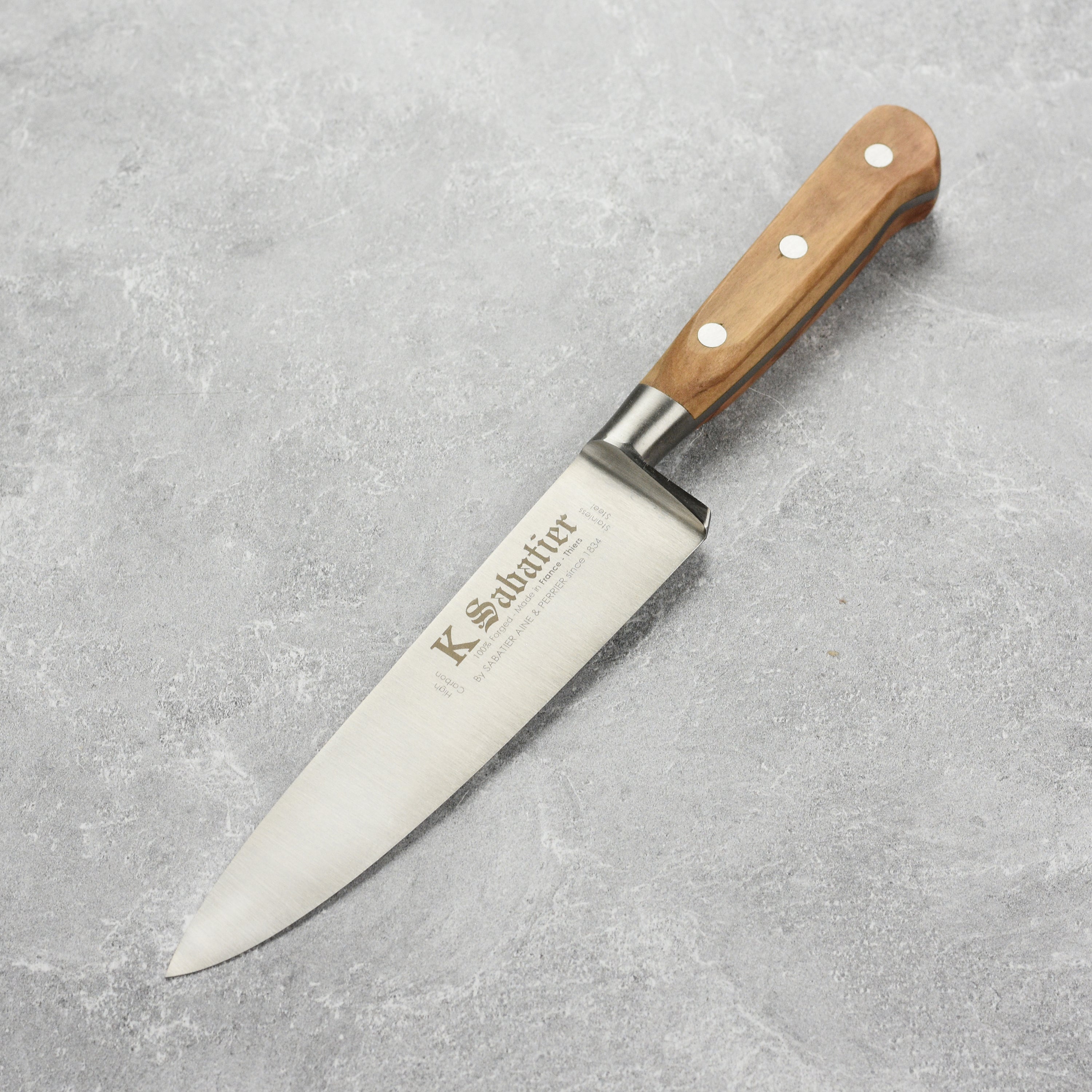Close-up of the K Sabatier Premium Olive Wood Chef's Knife highlighting the olive wood handle and stainless steel rivets.