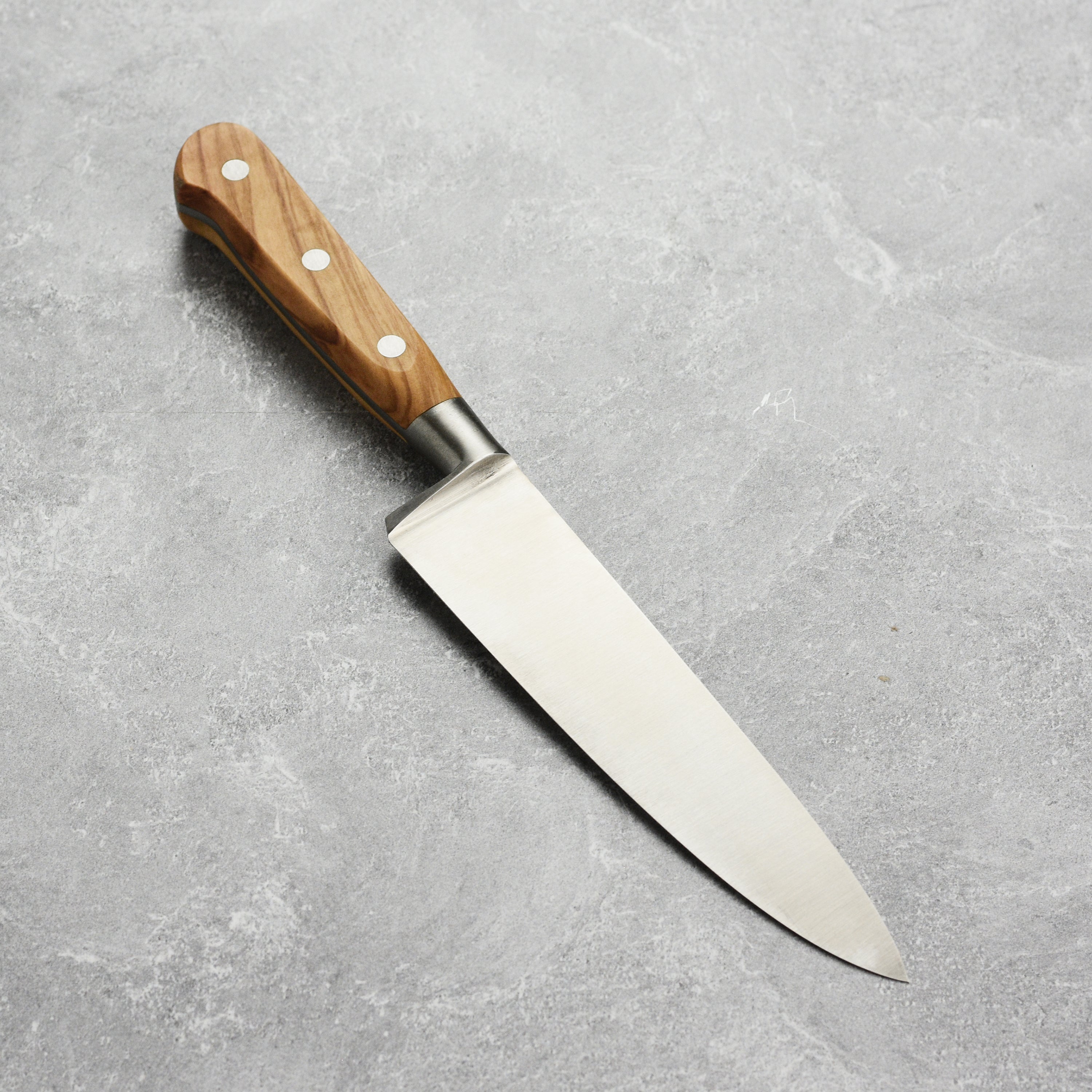 K Sabatier Premium Olive Wood Chefs Knife in action, slicing fresh vegetables on a wooden cutting board.
