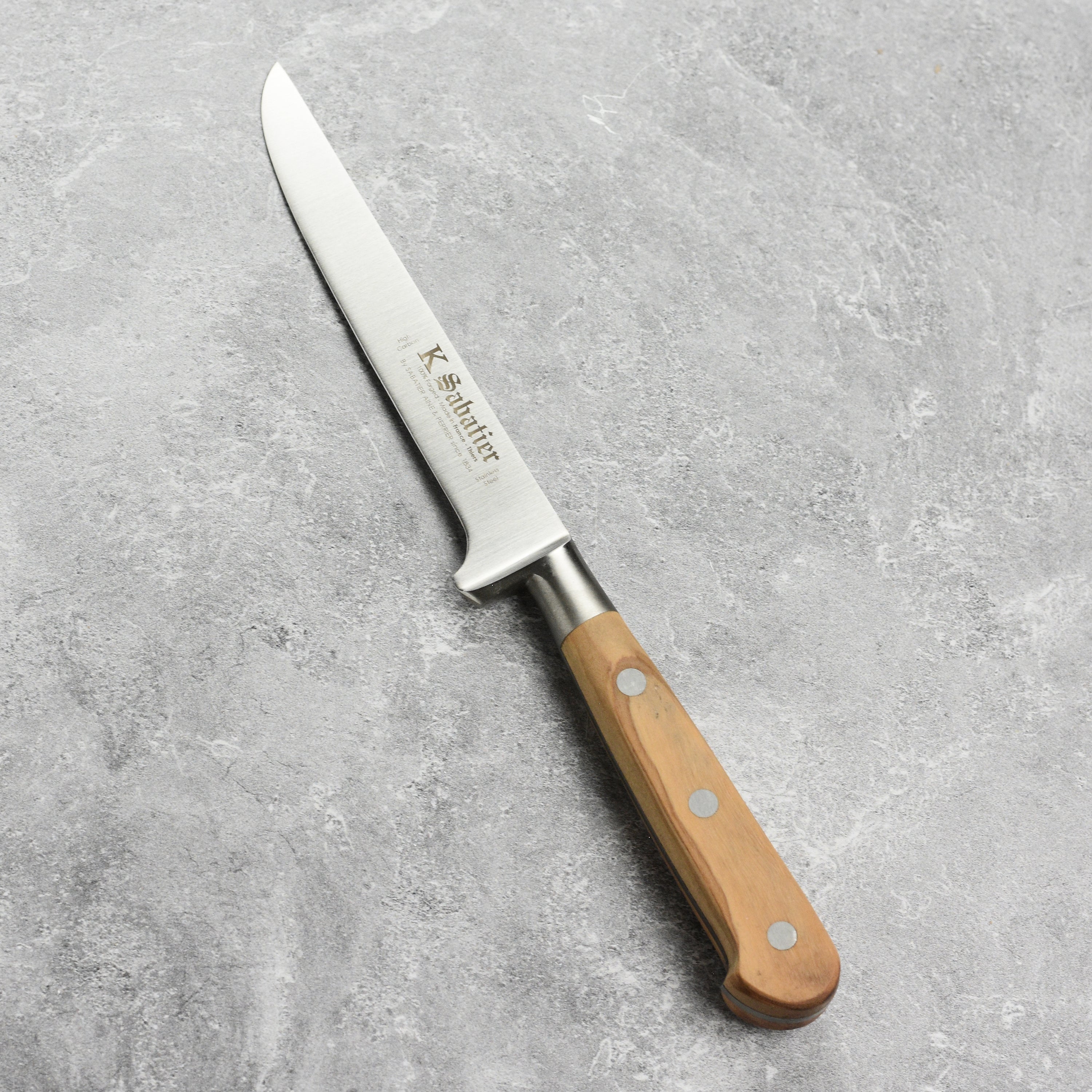 Sabatier Olive Wood Boning Knife being used to debone meat, demonstrating its precision and craftsmanship