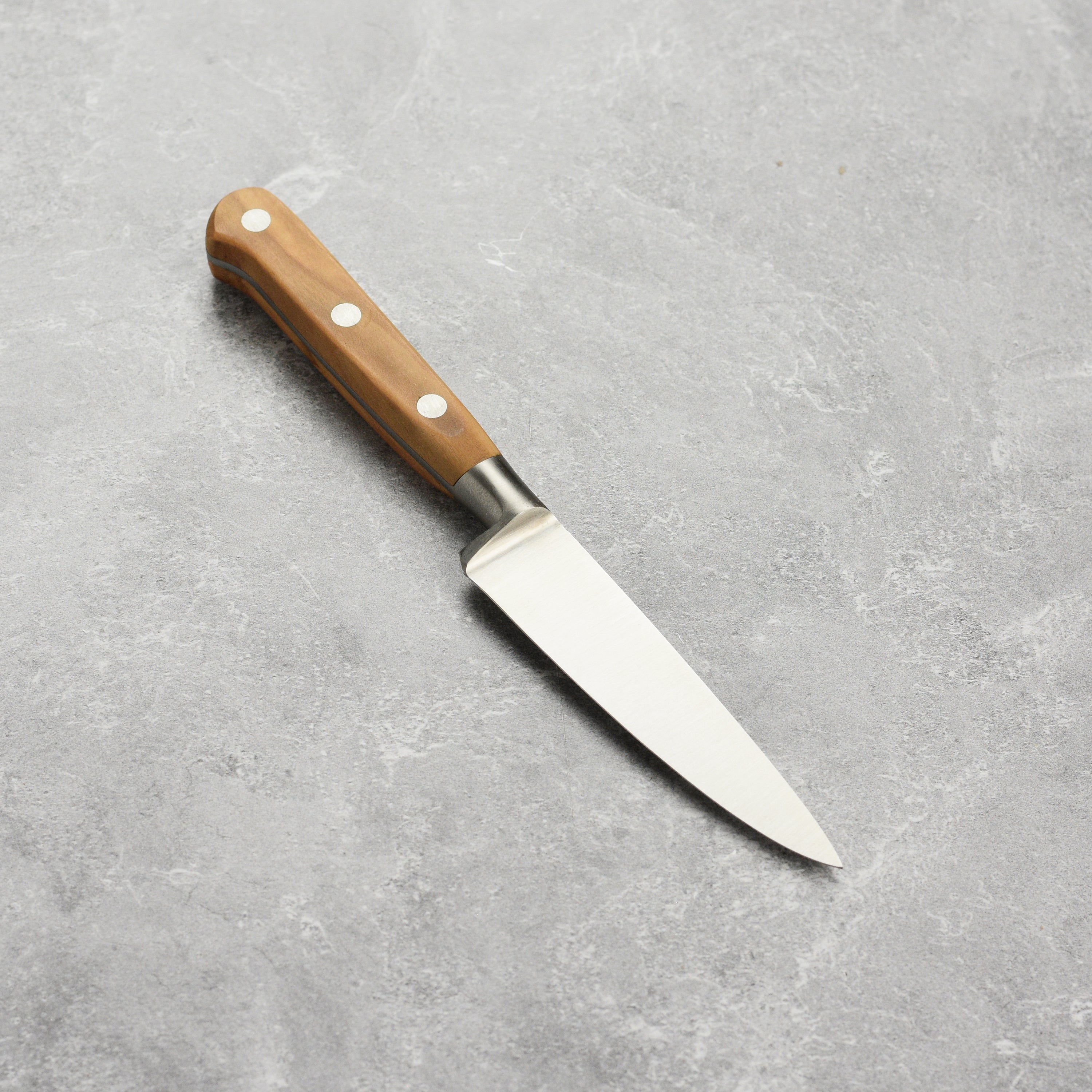 The olive wood handle of the K Sabatier paring knife, emphasizing its craftsmanship and ergonomic grip.