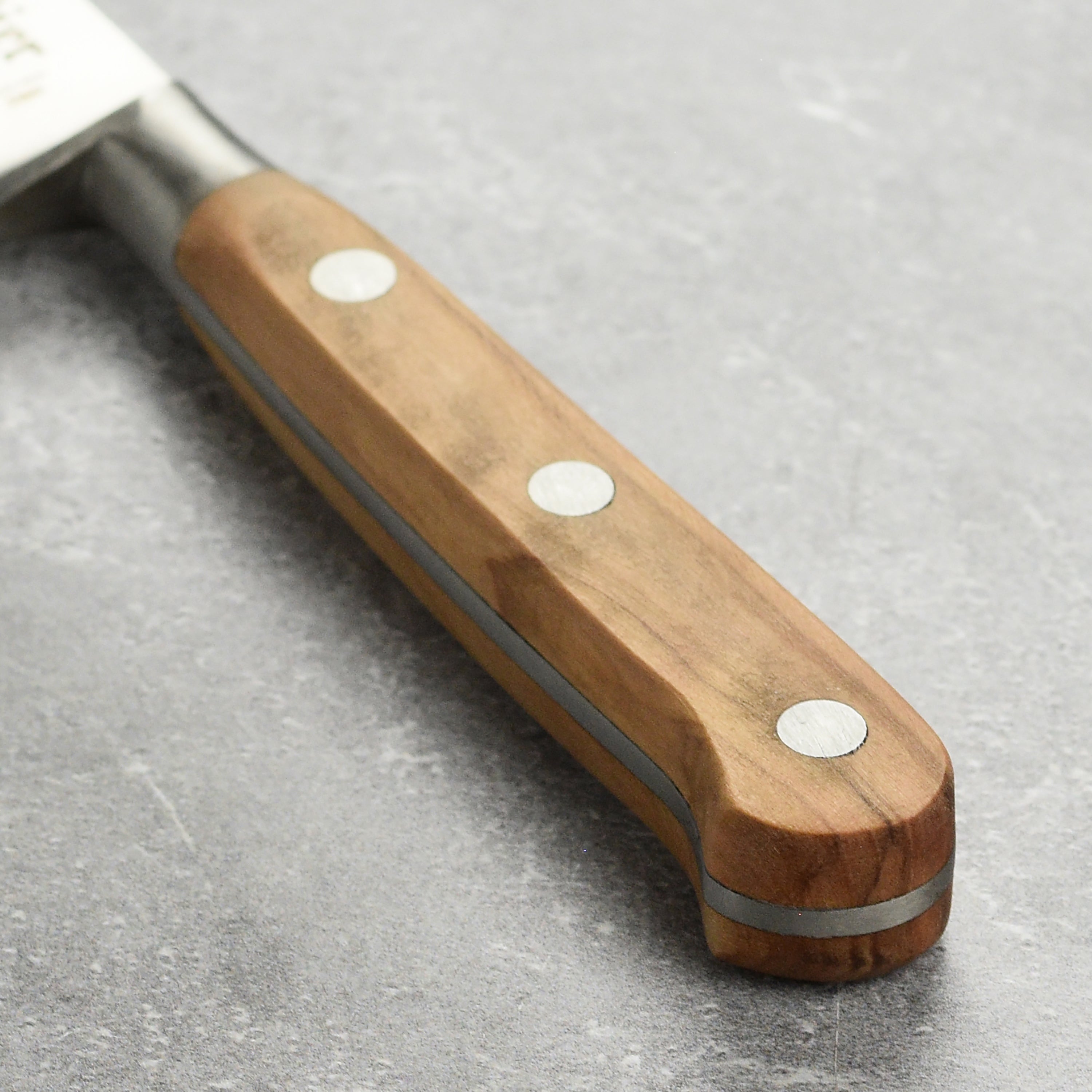 The olive wood handle of the K Sabatier paring knife, emphasizing its craftsmanship and ergonomic grip.