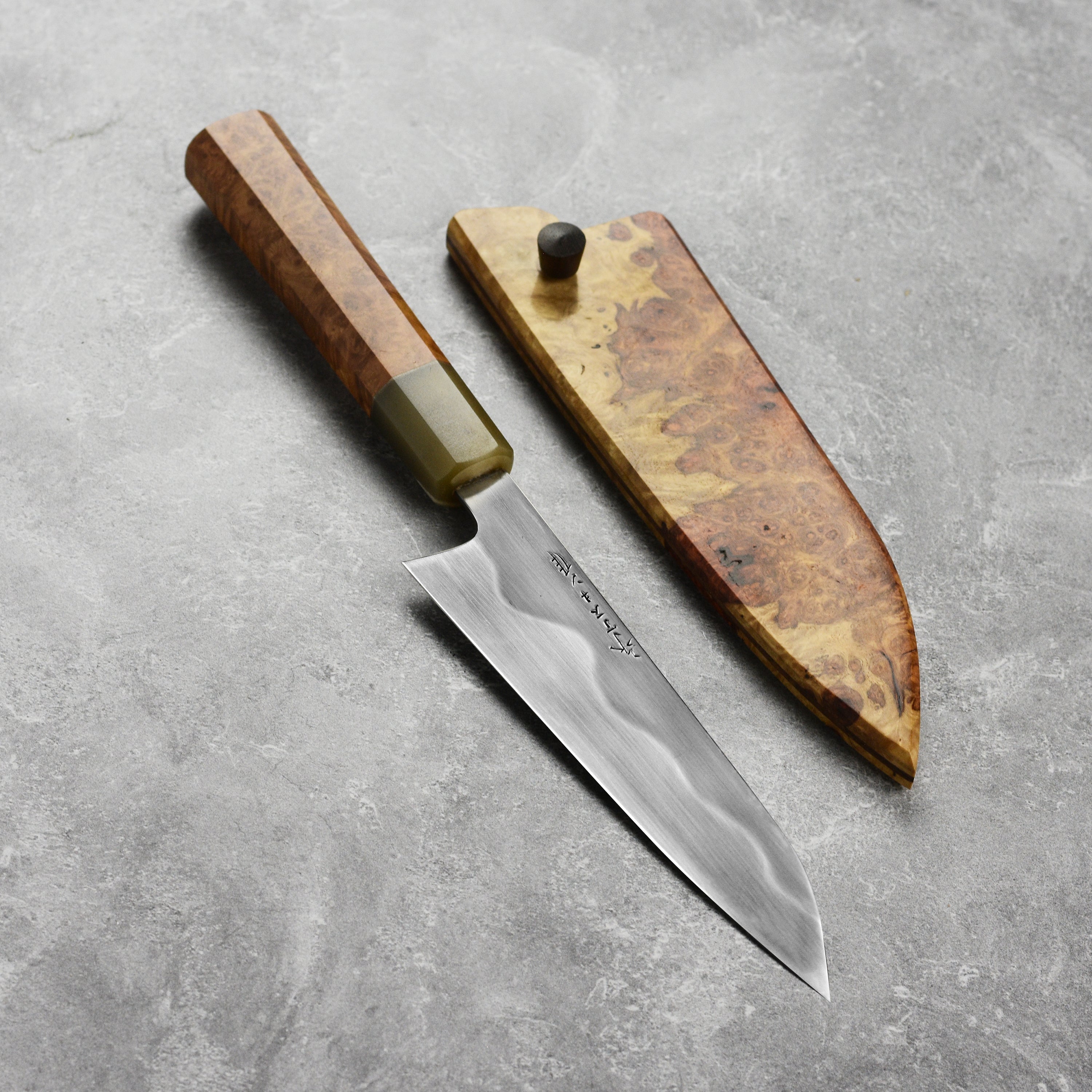 Hand-forged carbon steel petty knife with saya, showcasing sharp blade and ergonomic handle.