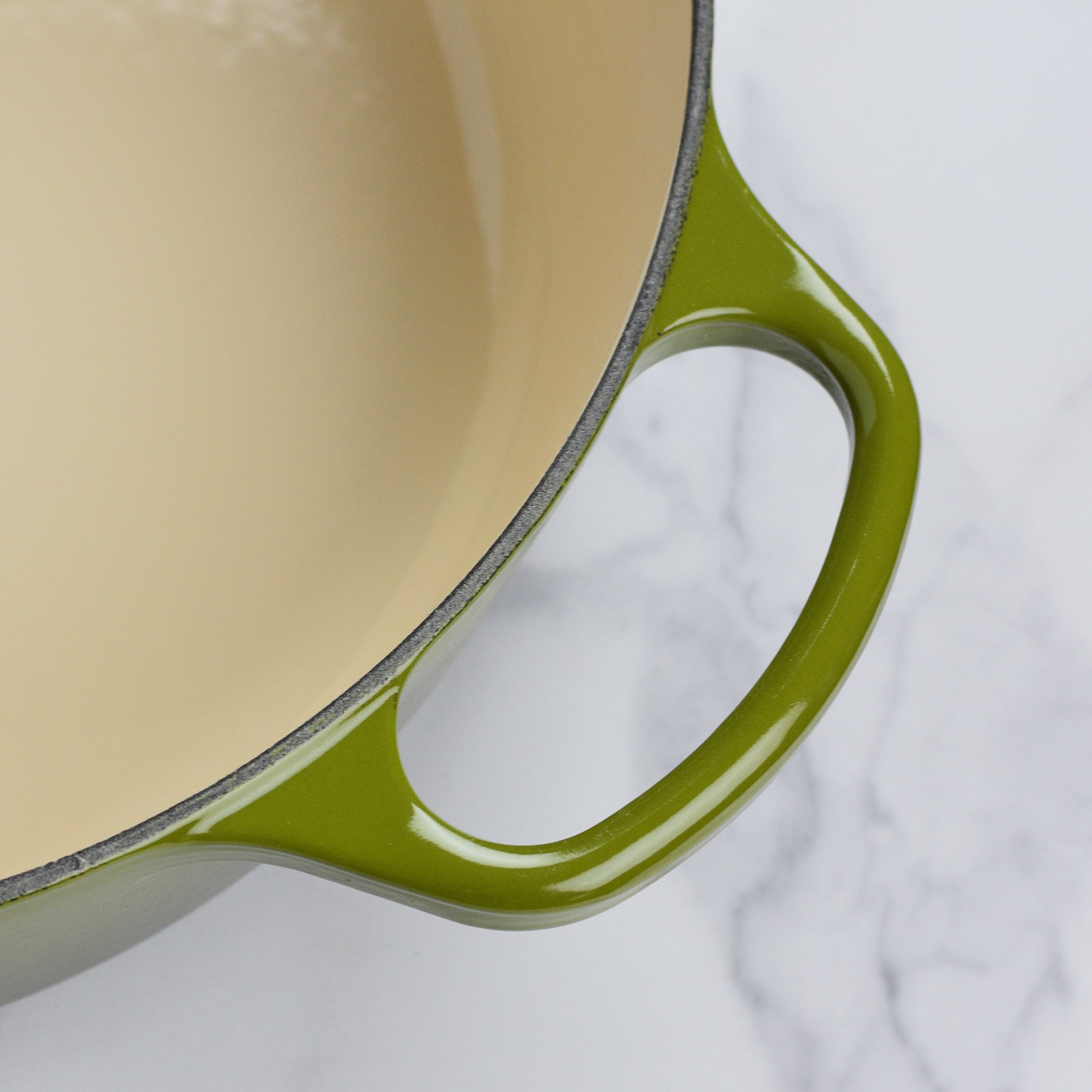 Signature enameled Dutch oven with ergonomic handles and gold knob from a top angle.