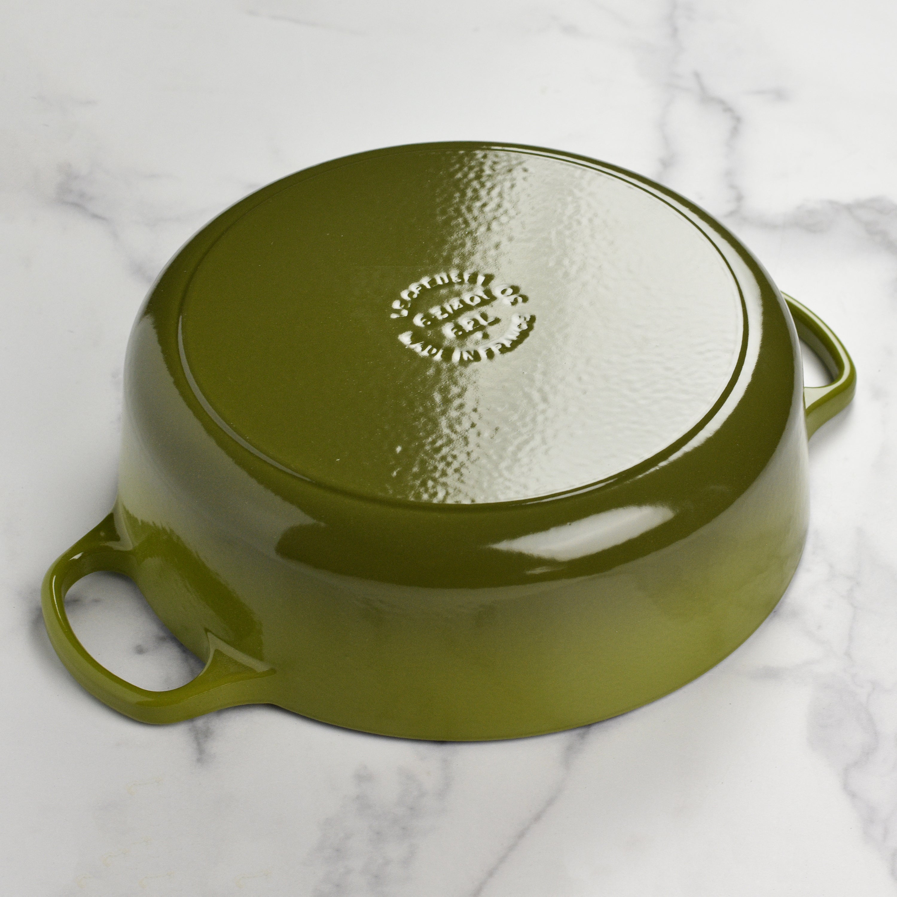 Signature enameled Dutch oven with ergonomic handles and gold knob from a top angle.