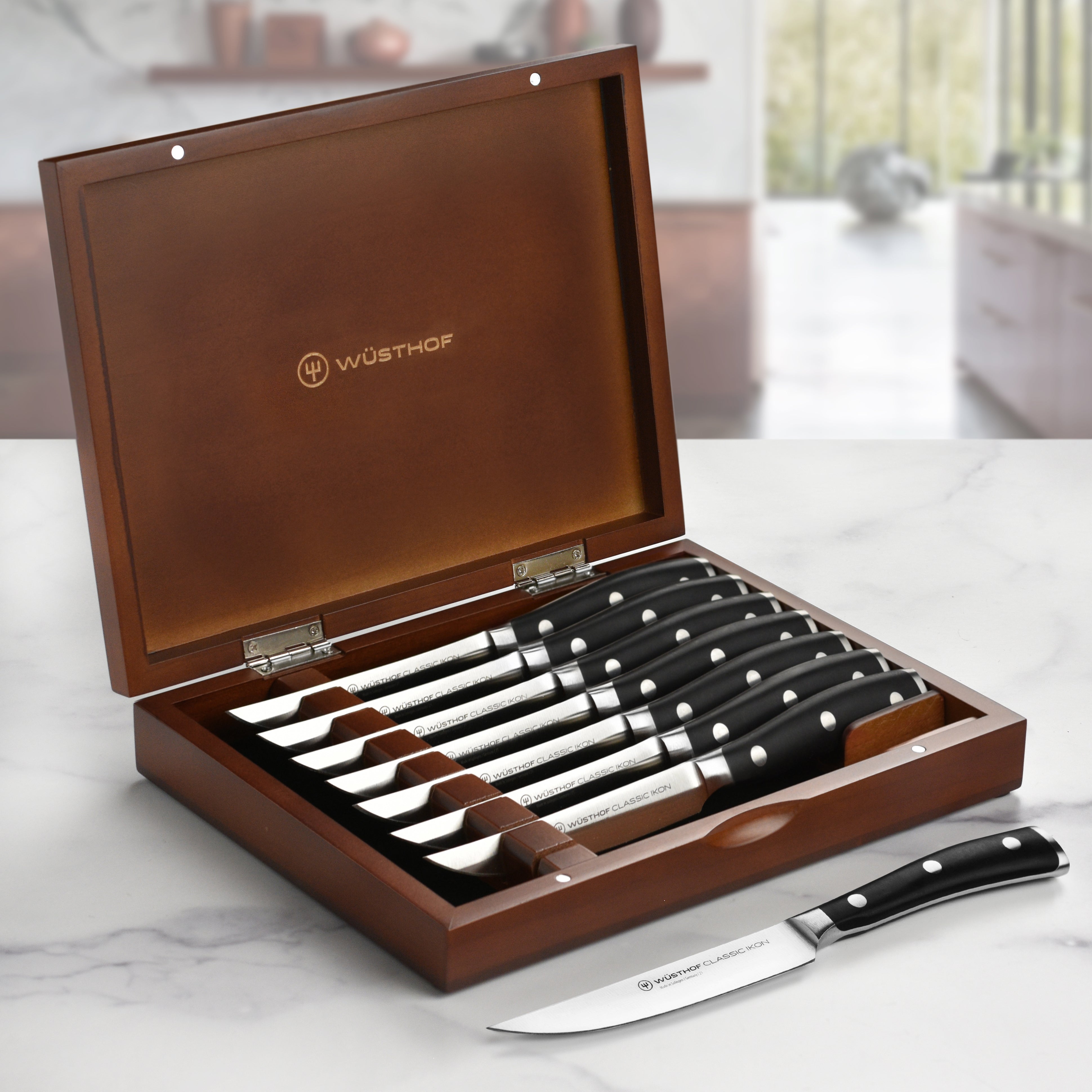 Close-up of Wusthof Classic Ikon steak knives with wooden case, highlighting blade sharpness and handle design