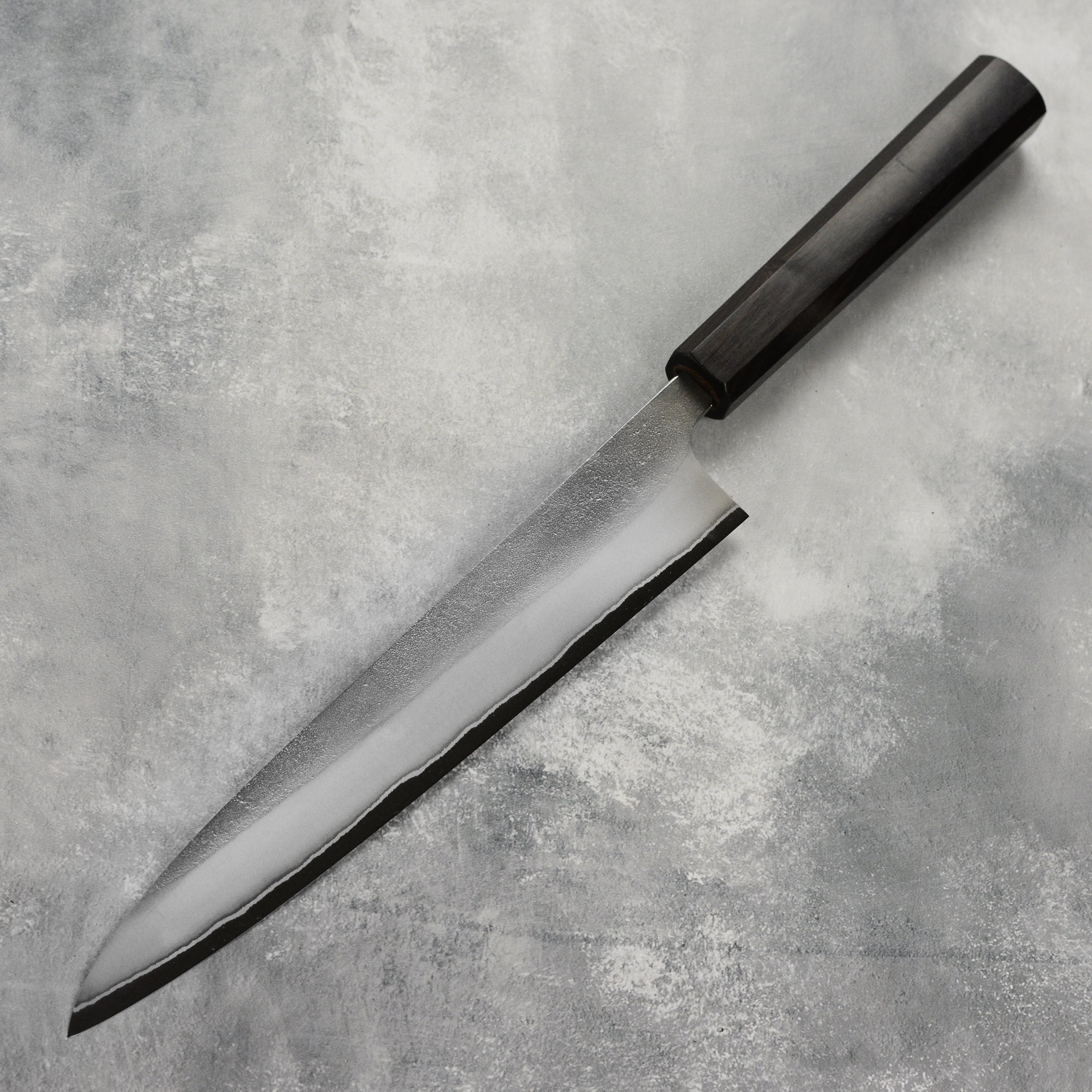 Chef slicing fish with Yoshikane Japanese sujihiki in a professional kitchen