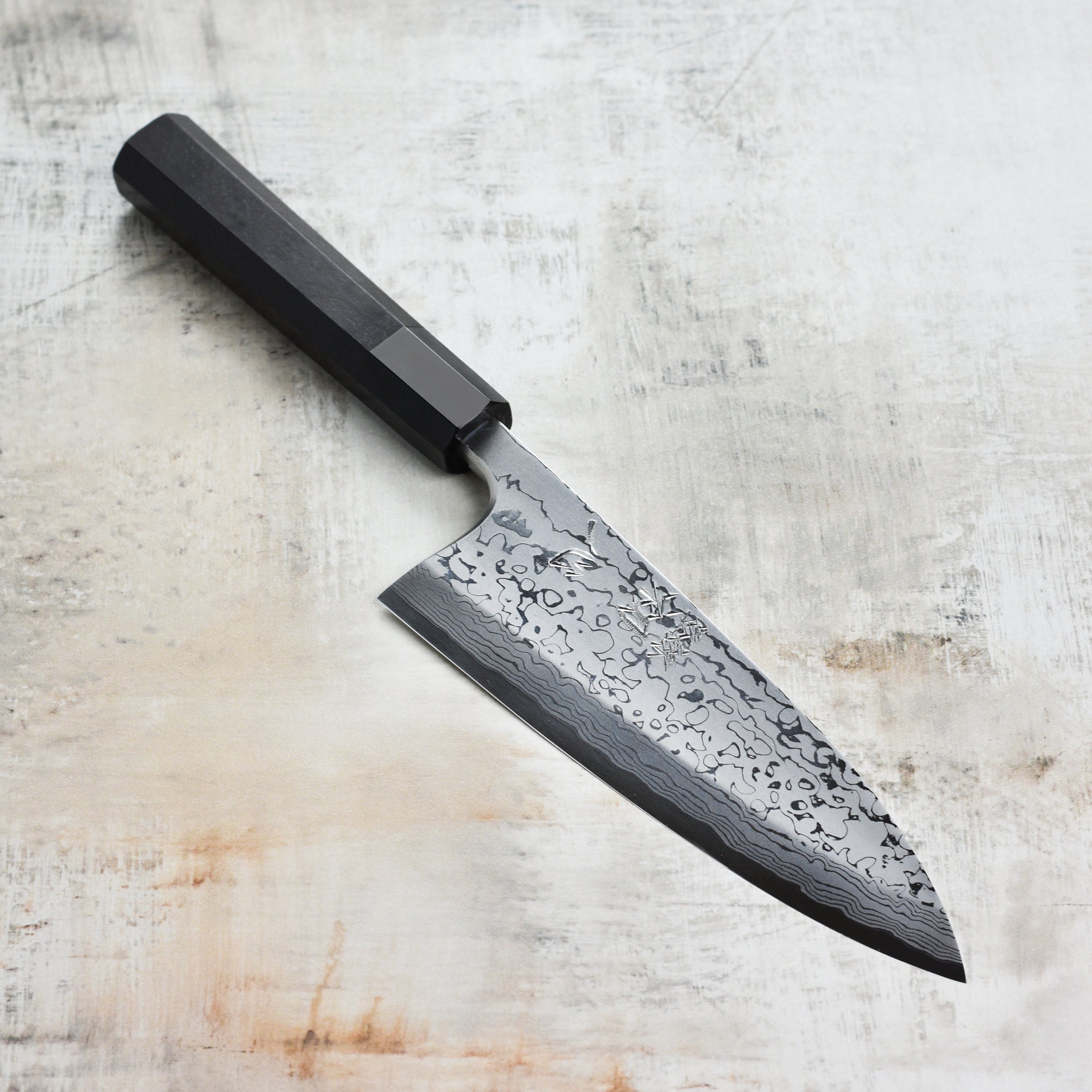 Hatsukokoro Aogami #2 Damascus Deba Knife angled view, showcasing its sharp edge and beautiful Damascus pattern.