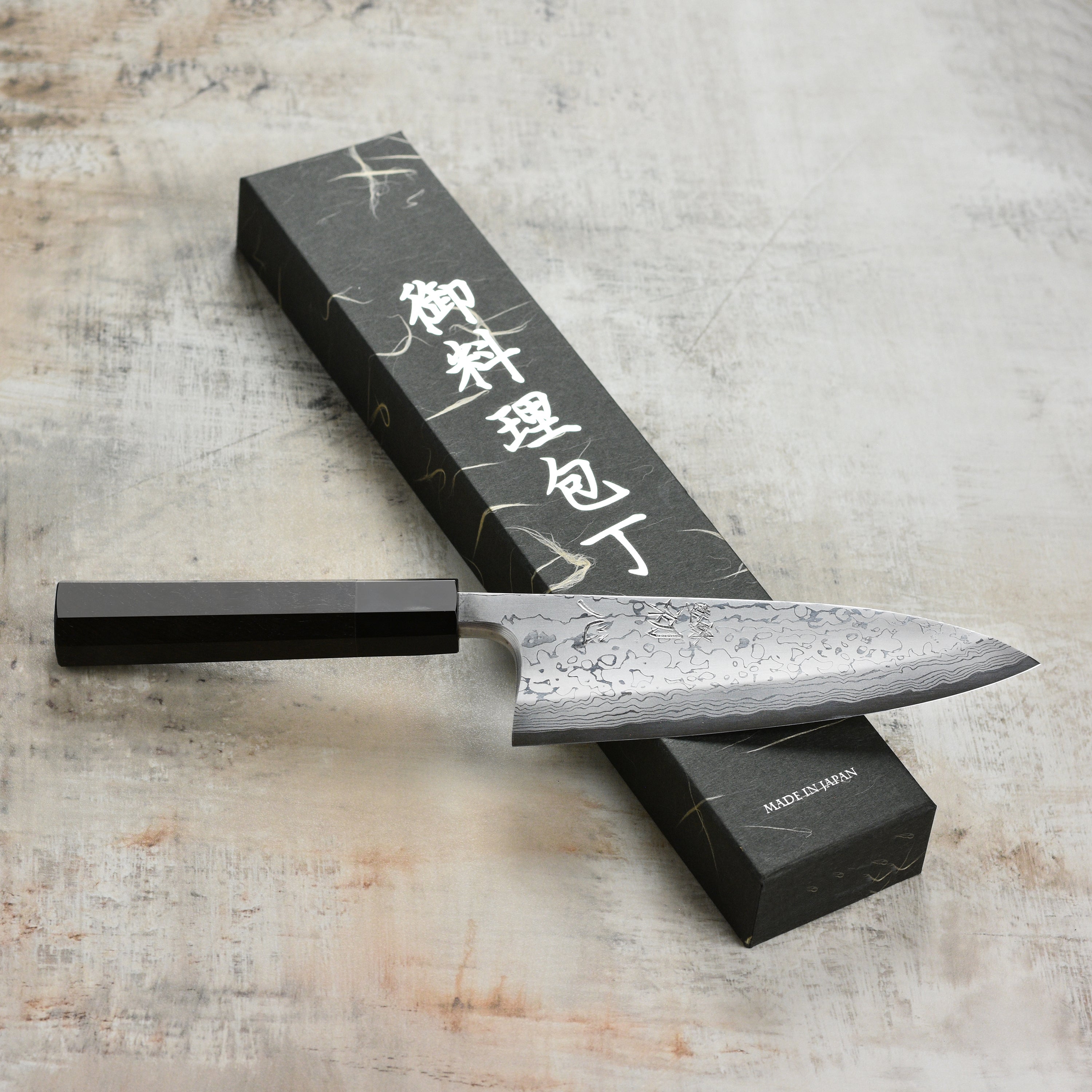 Hatsukokoro Aogami #2 Damascus Deba Knife angled view, showcasing its sharp edge and beautiful Damascus pattern.