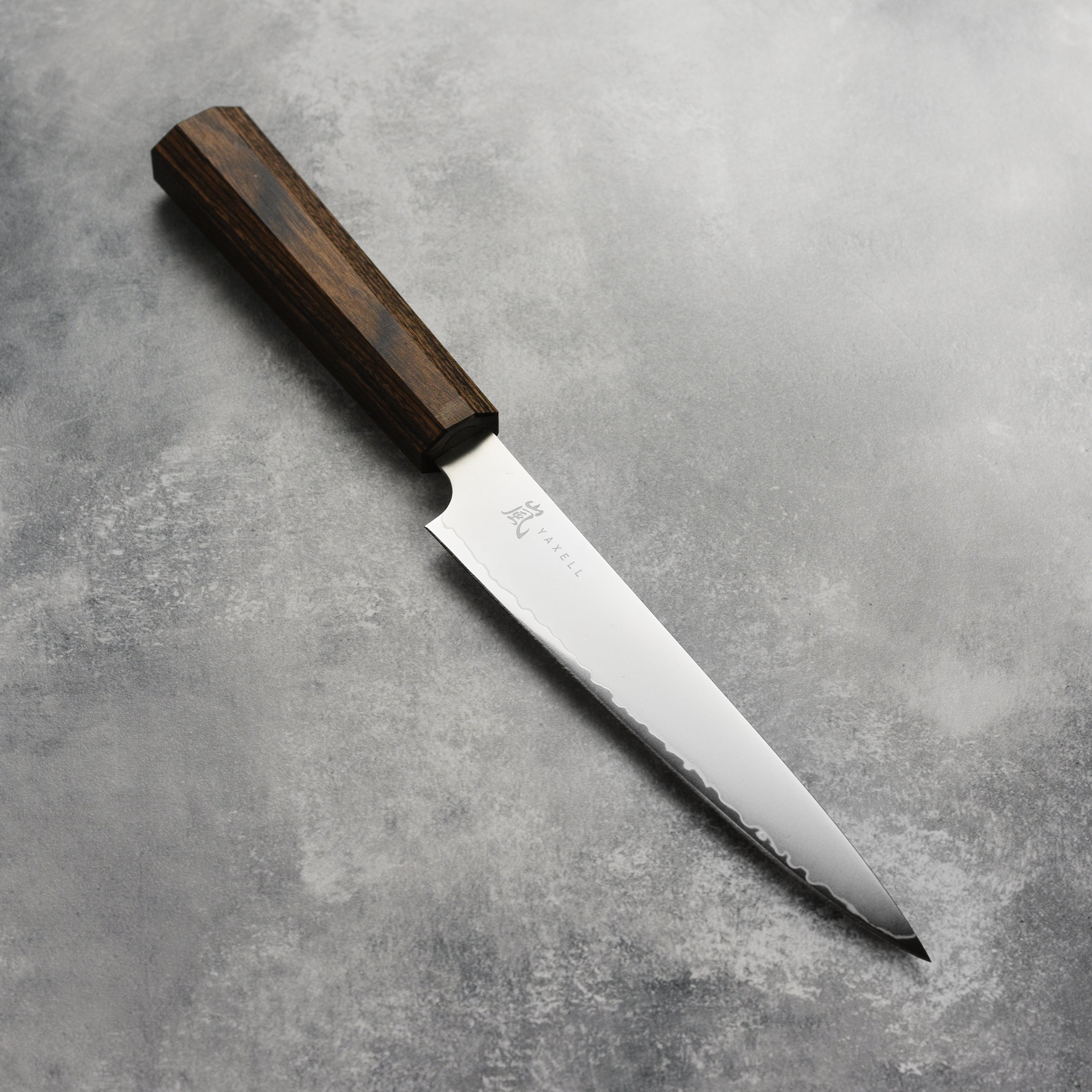 Yaxell Hana 6-inch Japanese utility knife with pakkawood handle on cutting board