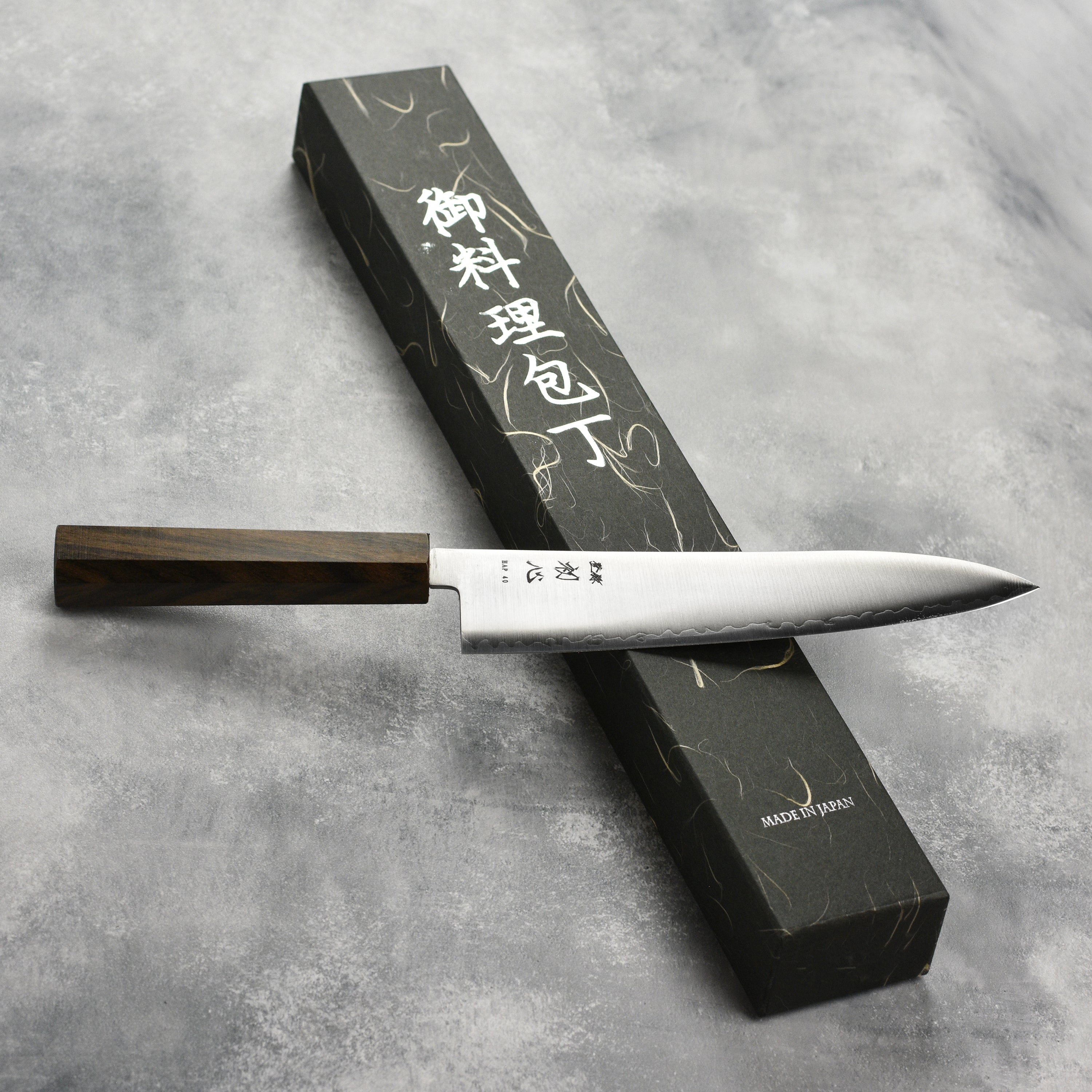 Hatsukokoro Hayabusa HAP40 Gyuto knife on a cutting board, ideal for professional chefs.