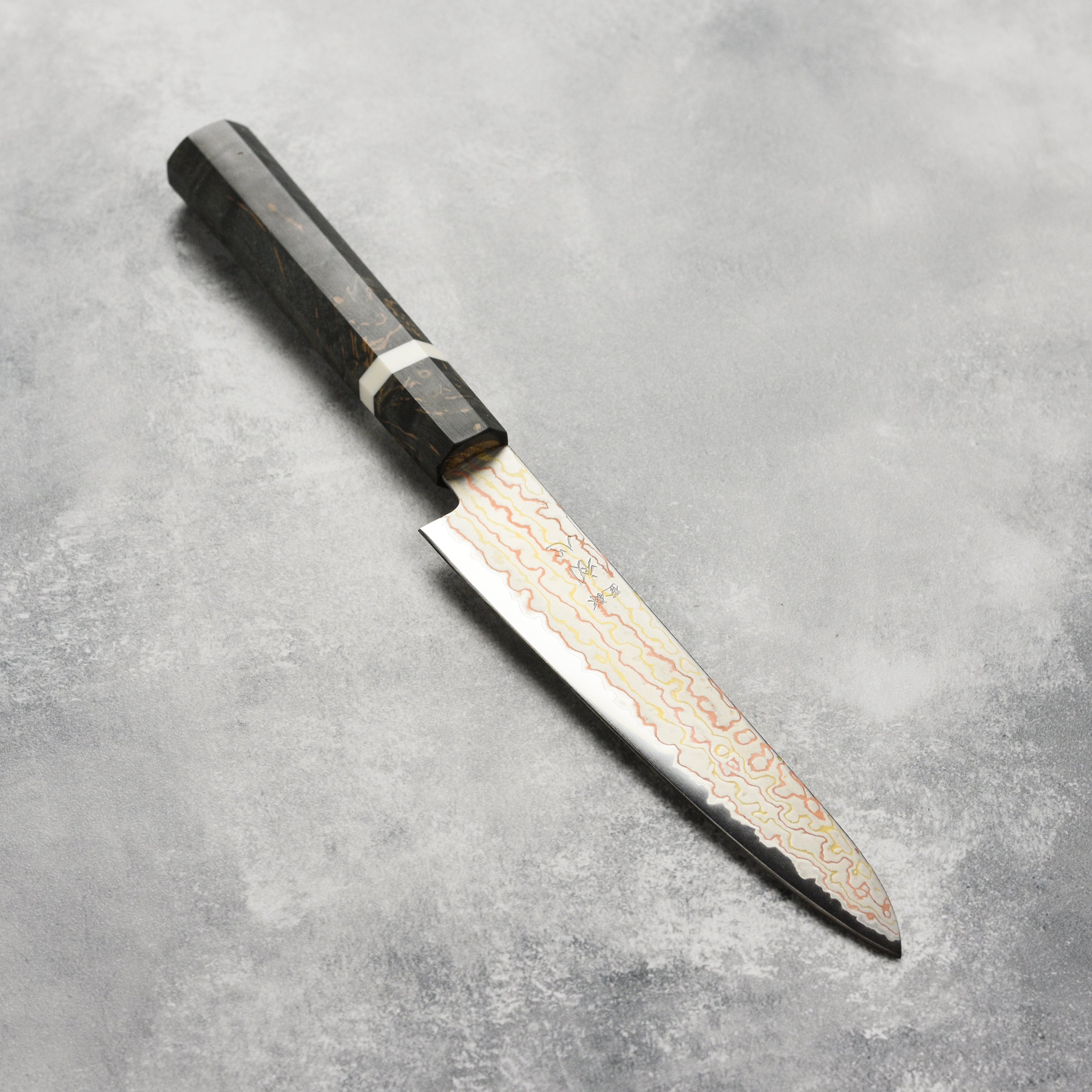 Close-up of the Hatsukokoro Hayabusa Aogami Rainbow Damascus Chef Knife highlighting its blade and handle.