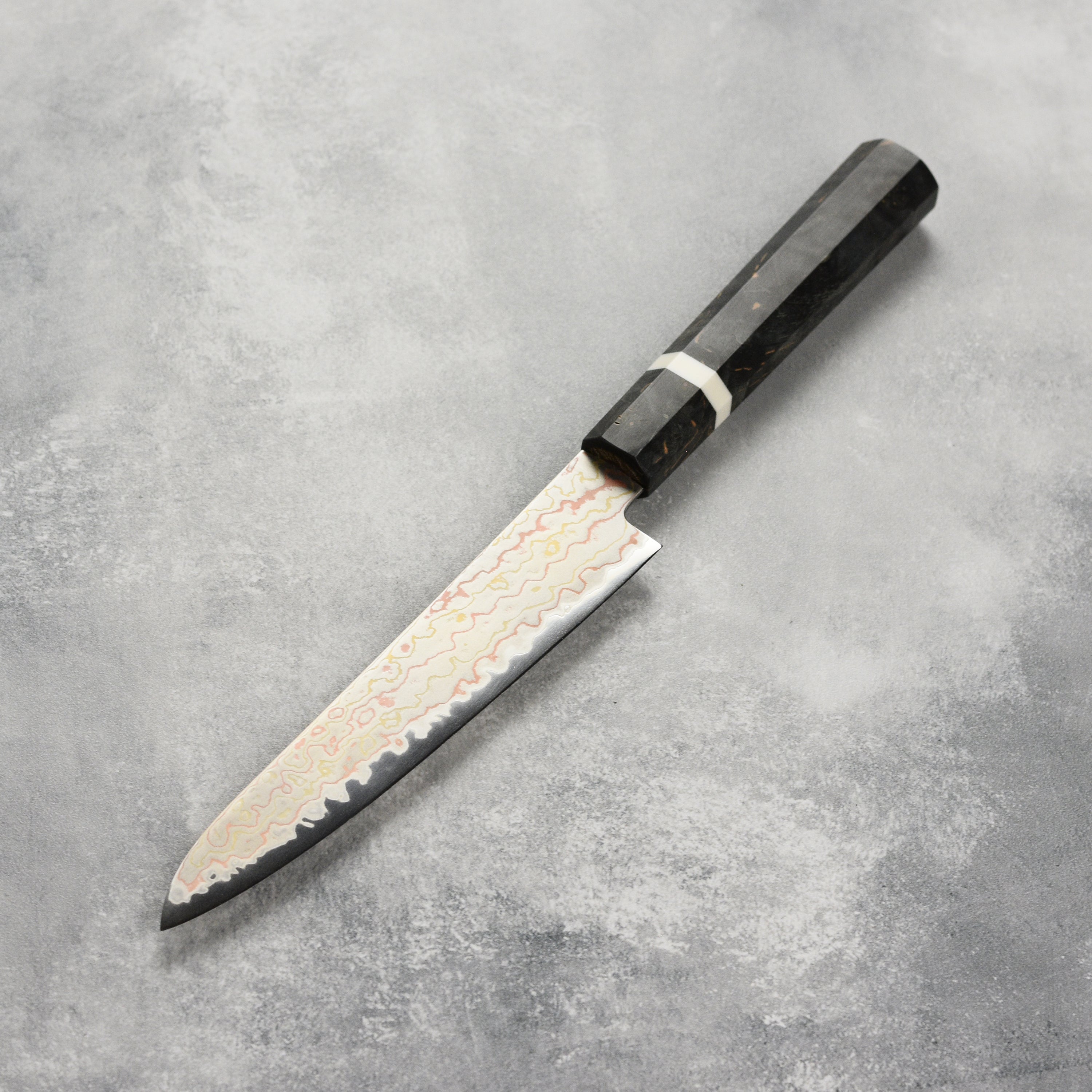 Close-up of the Hatsukokoro Hayabusa Aogami Rainbow Damascus Chef Knife highlighting its blade and handle.