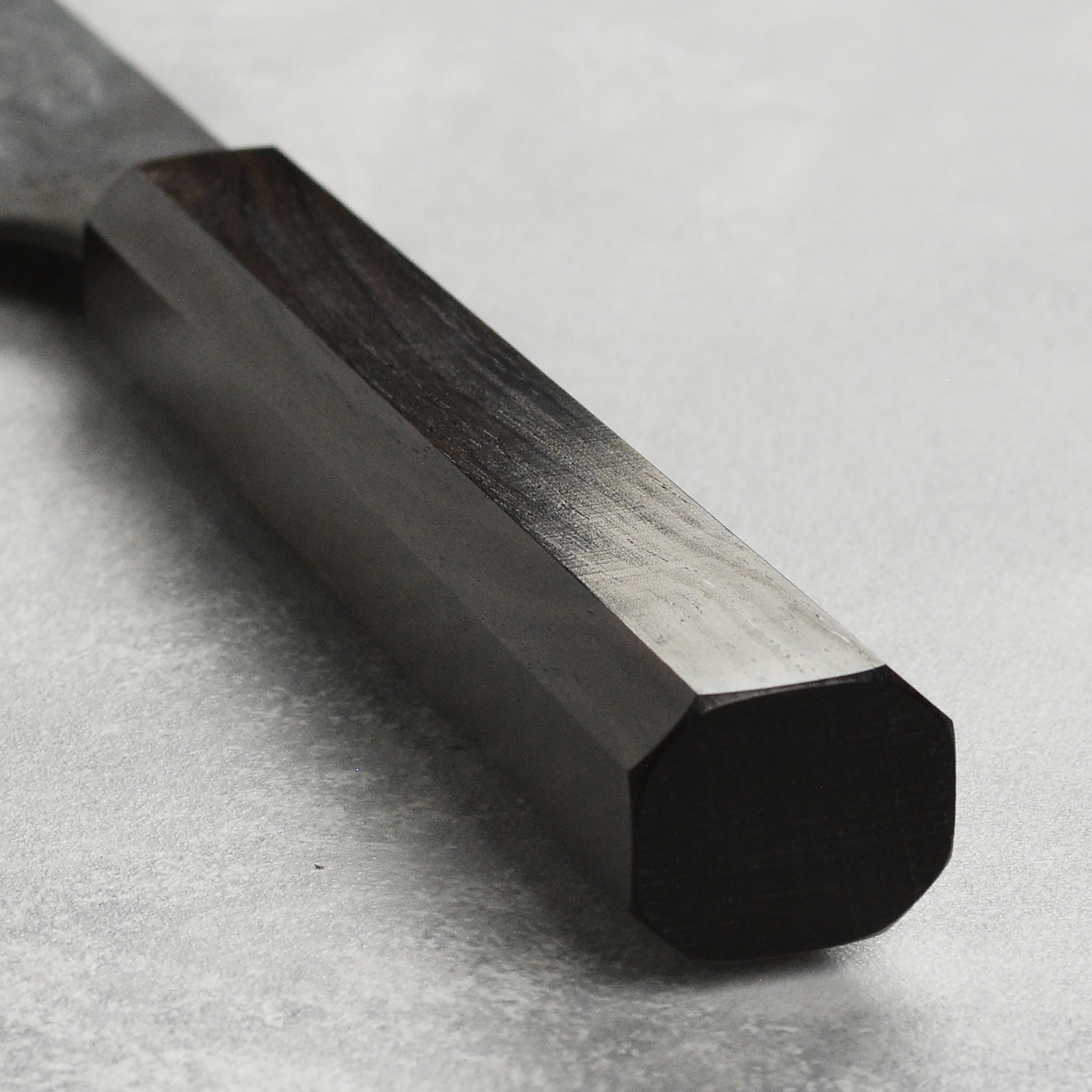 Close-up of the Hatsukokoro Santoku Knife on a wooden cutting board, highlighting its copper Damascus finish.