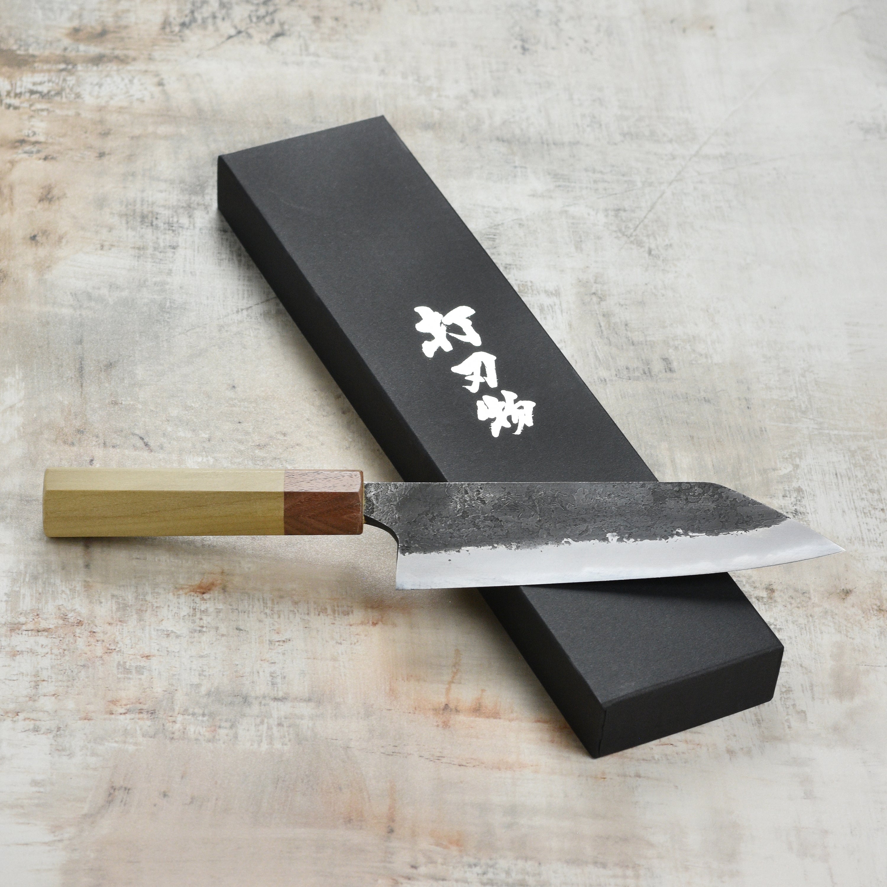 Mazaki Shirogami Santoku knife in action, expertly slicing through a piece of fish, demonstrating its versatility.