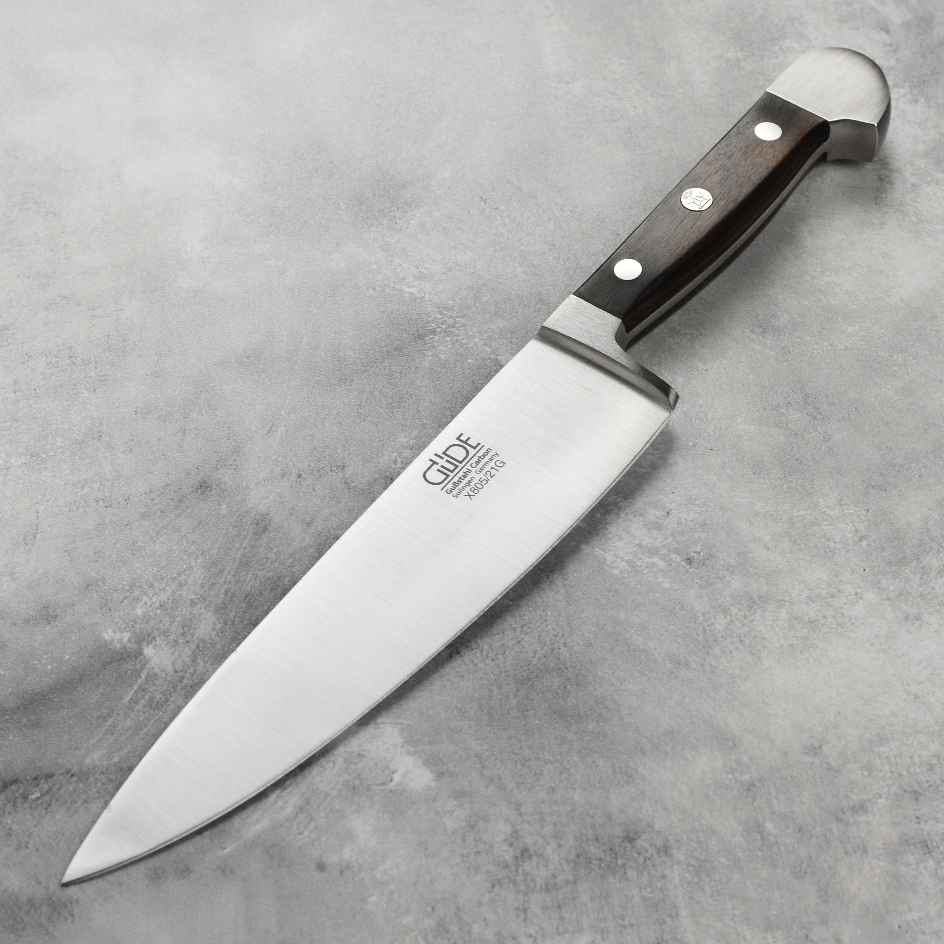 Gude Alpha Carbon chef's knife showcasing the sharp edge and elegant handle