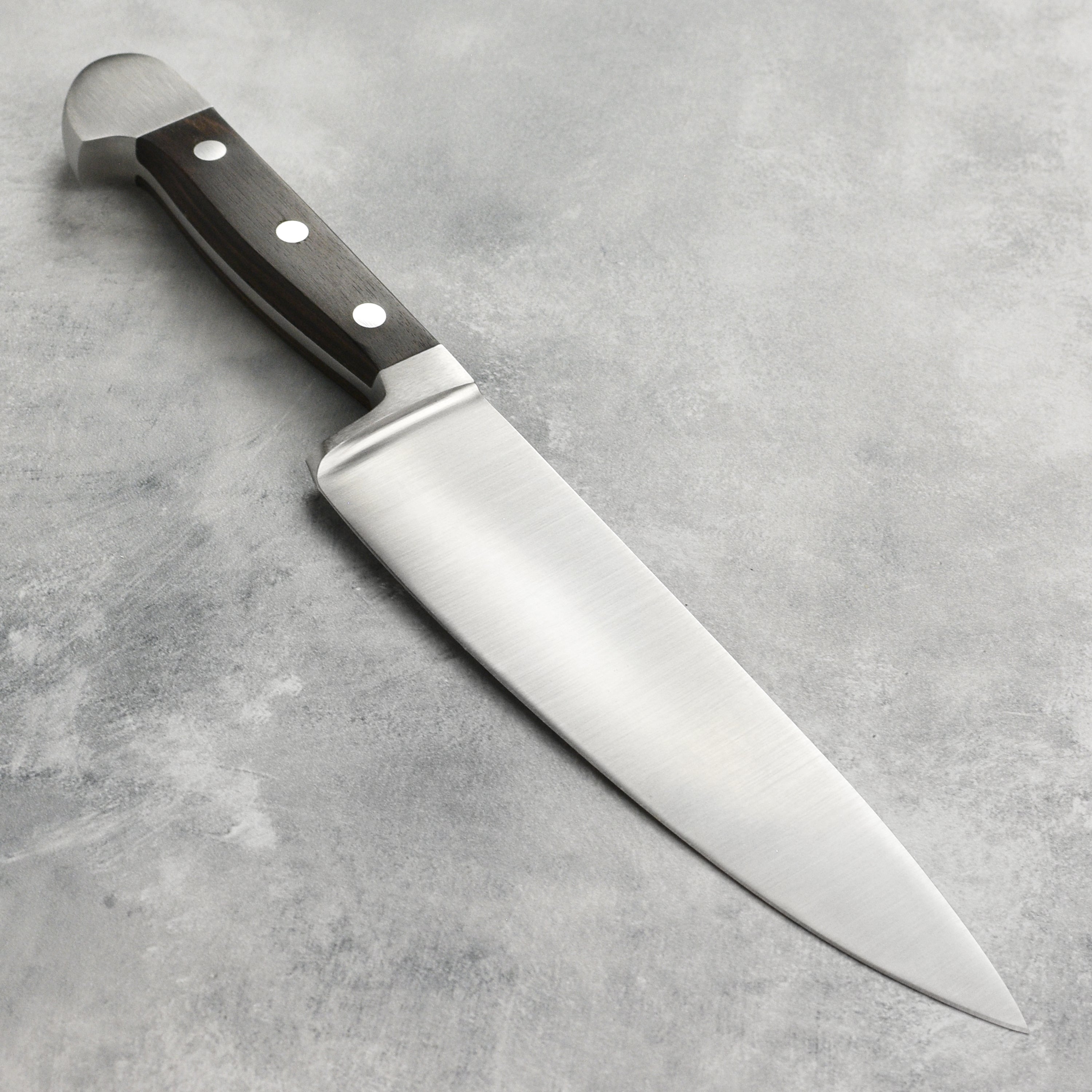 Gude Alpha Carbon chefs knife showcasing the sharp edge and elegant handle