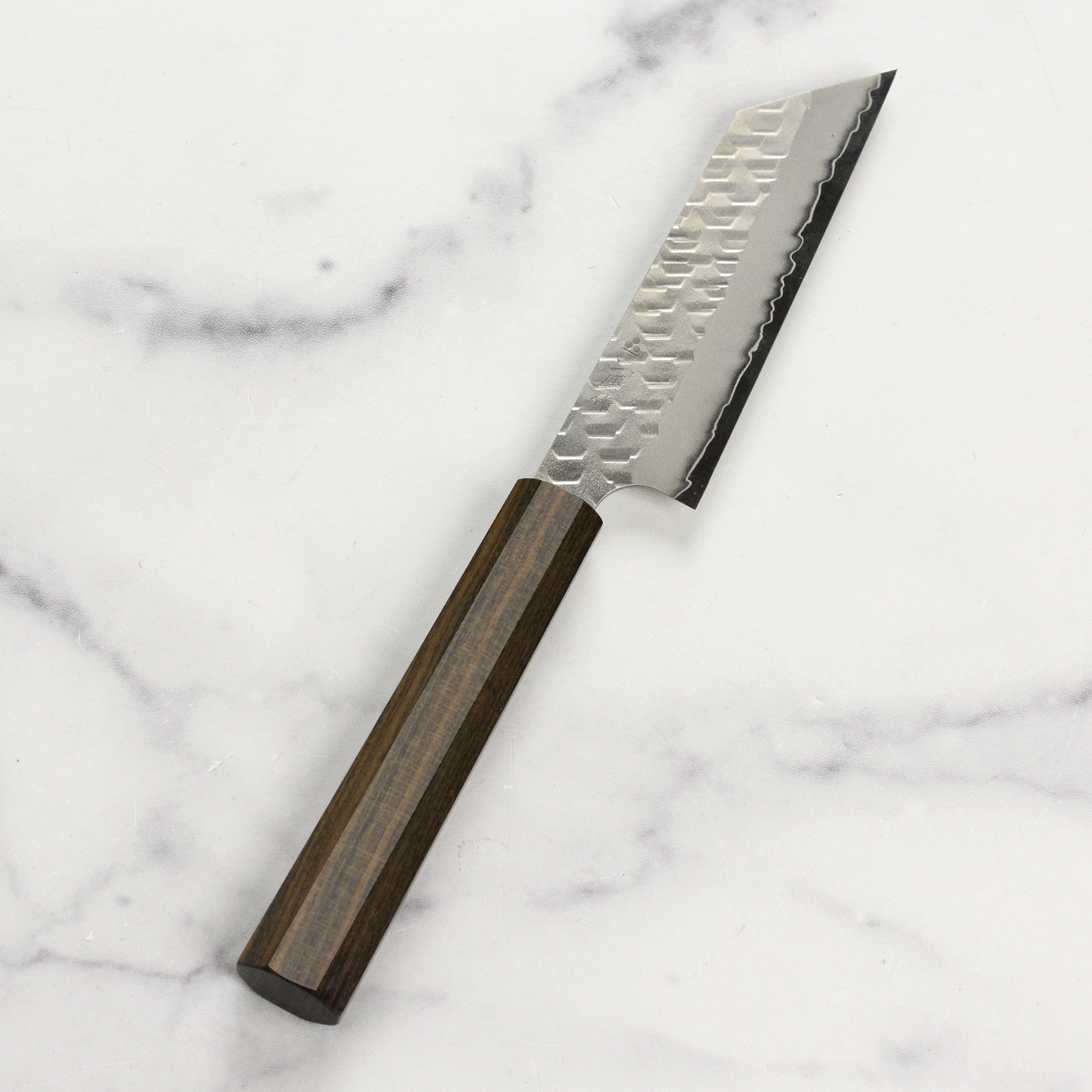 Close-up of the Nigara Kiritsuke Paring Knife on a cutting board, highlighting its precision and quality.