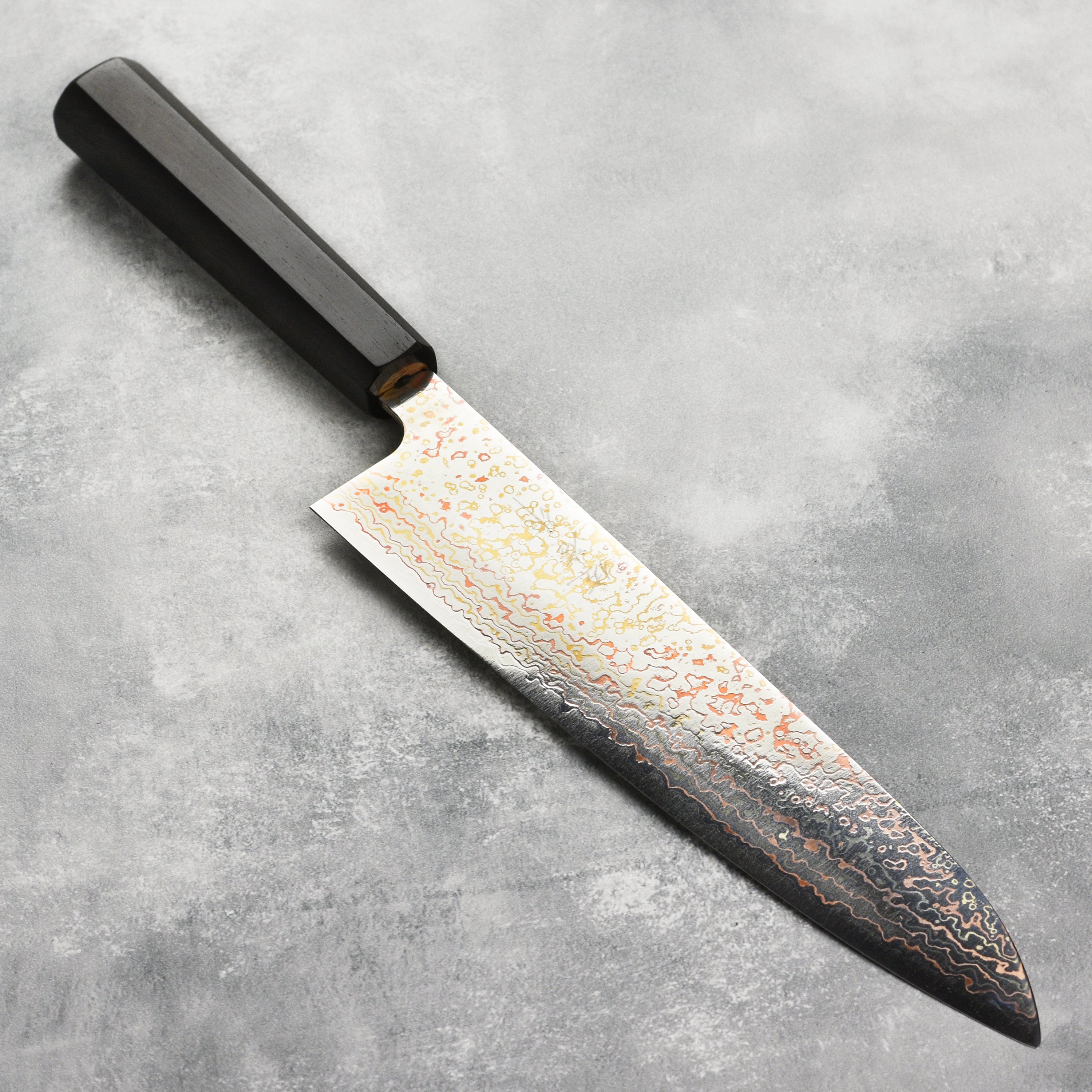 Saji Rainbow Damascus Gyuto knife displaying its intricate blade design and colorful finish.