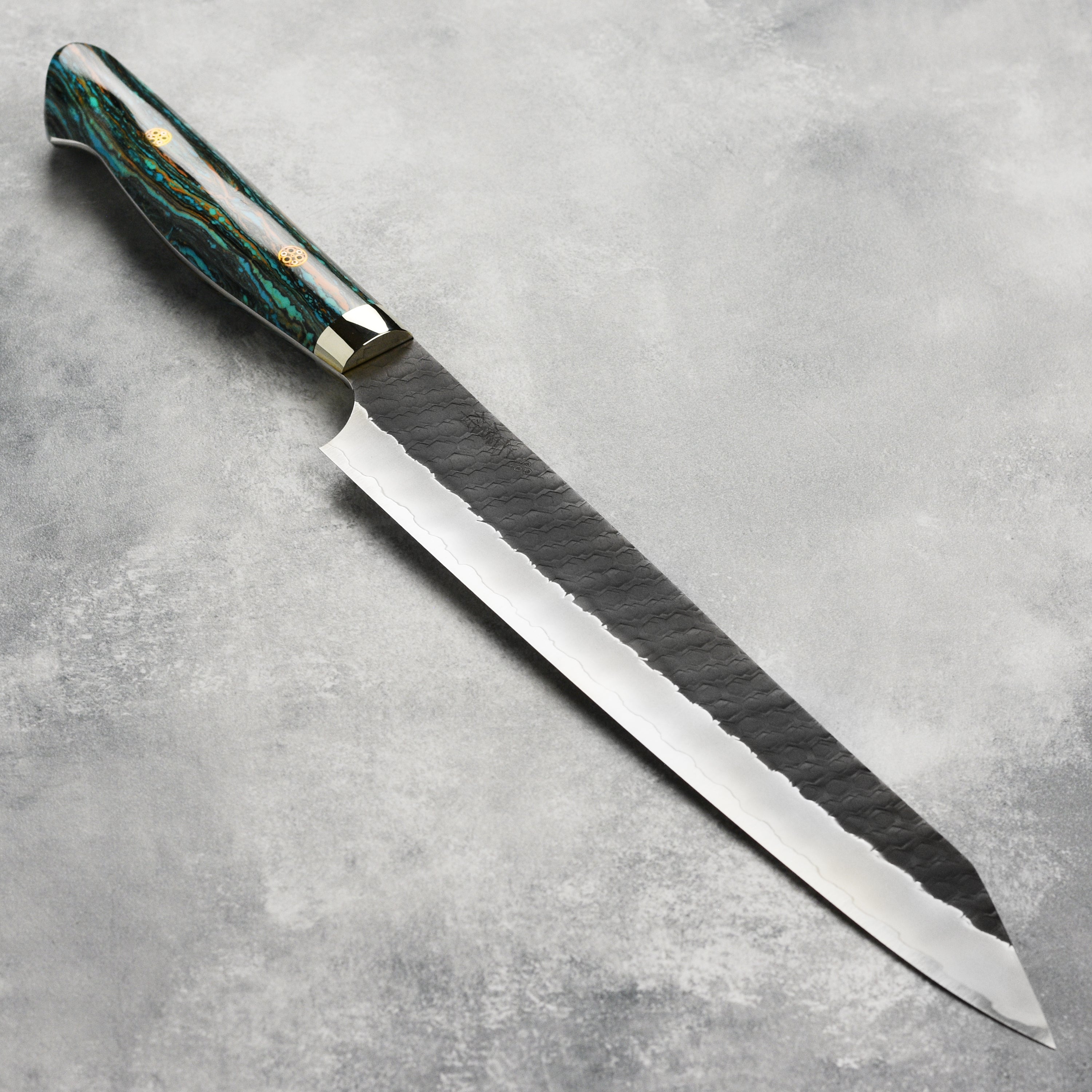 Close-up of Nigara SG2 Kurouchi Tsuchime 10-inch kiritsuke highlighting its textured surface and sharp edge