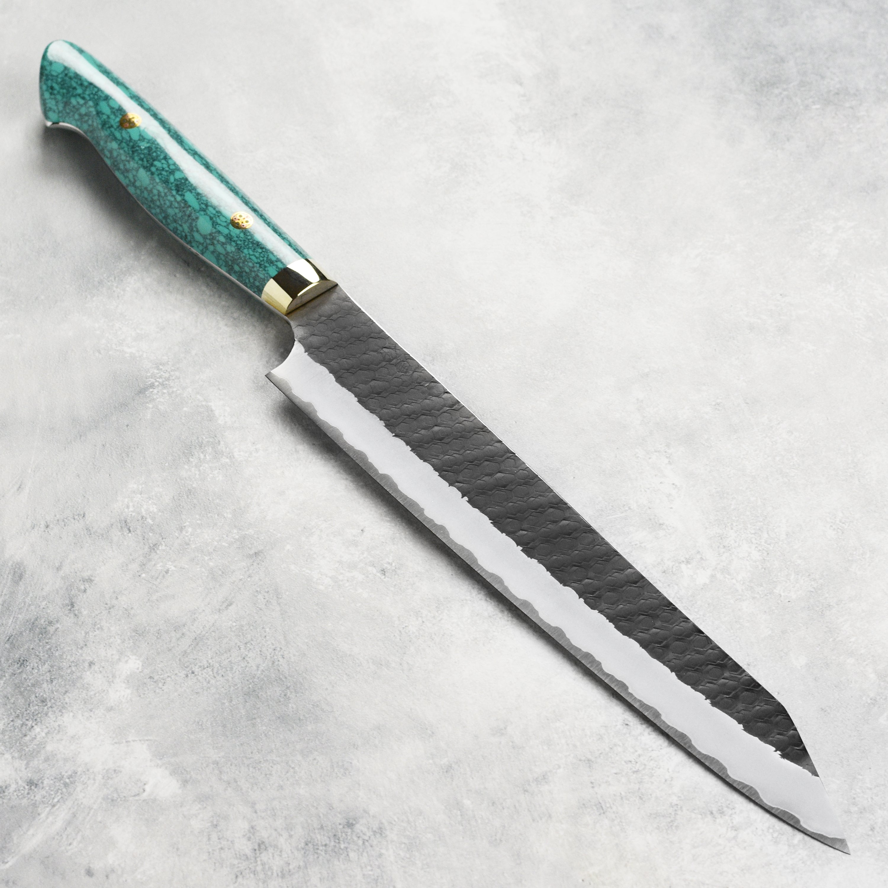 Nigara SG2 Kiritsuke Sujihiki knife showcasing its sleek green turquoise design and sharp blade, perfect for professional chefs.
