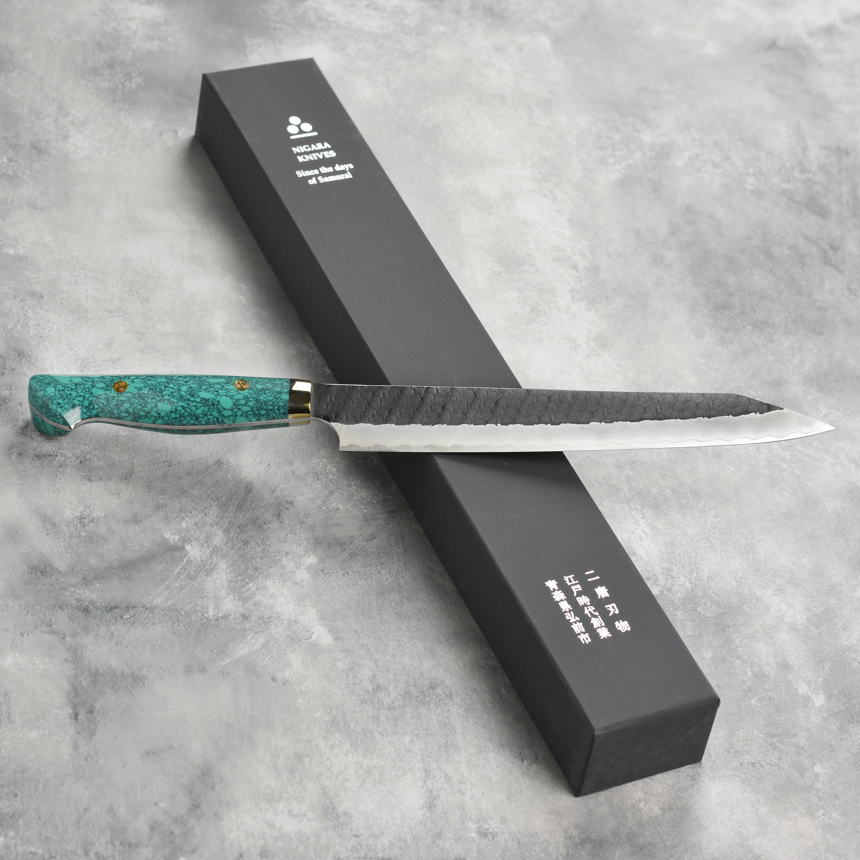 Nigara SG2 Kiritsuke Sujihiki in action on a cutting board, illustrating its versatility for various culinary tasks.