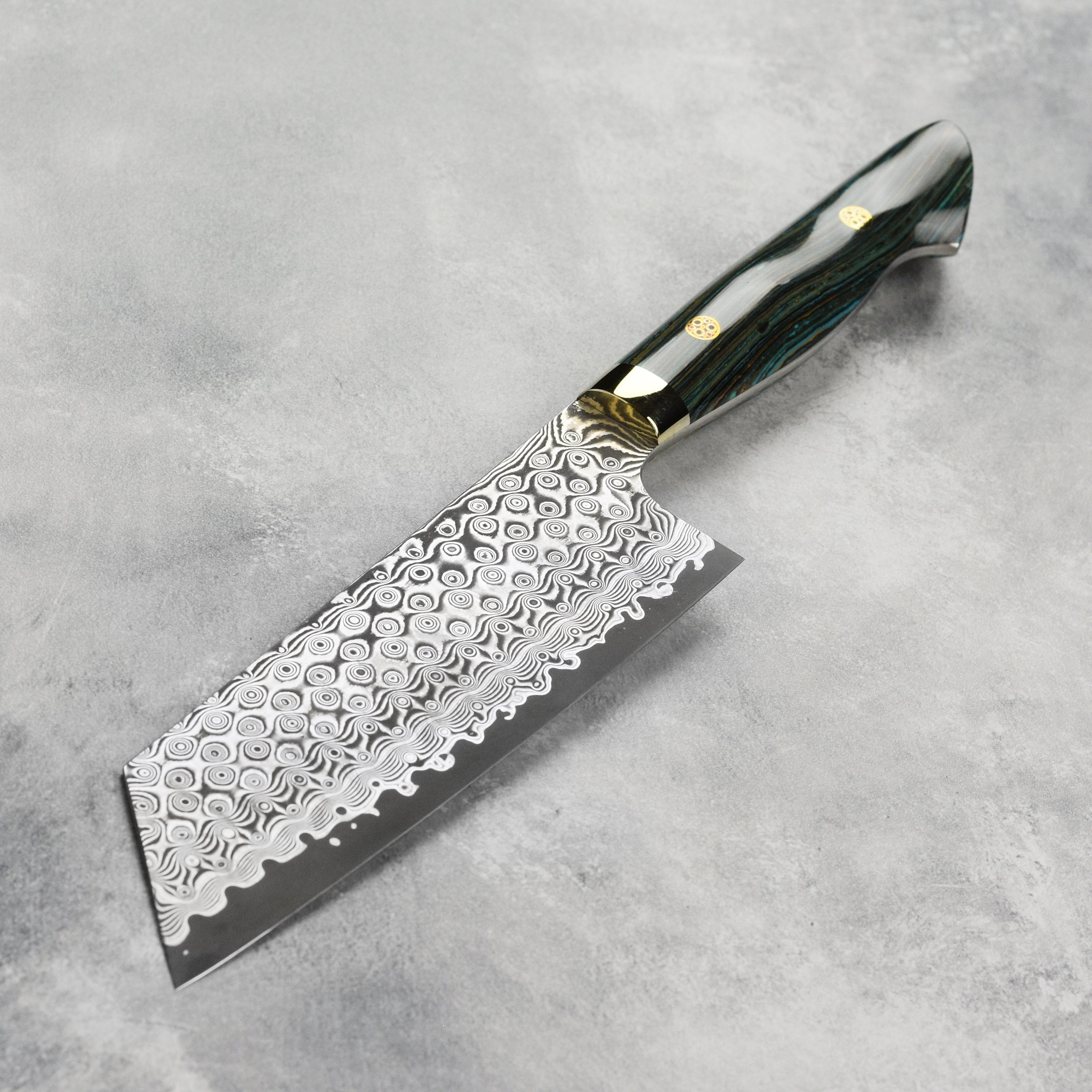 Close-up view of the turquoise striped Damascus kiritsuke knife showcasing its sharp edge and craftsmanship.