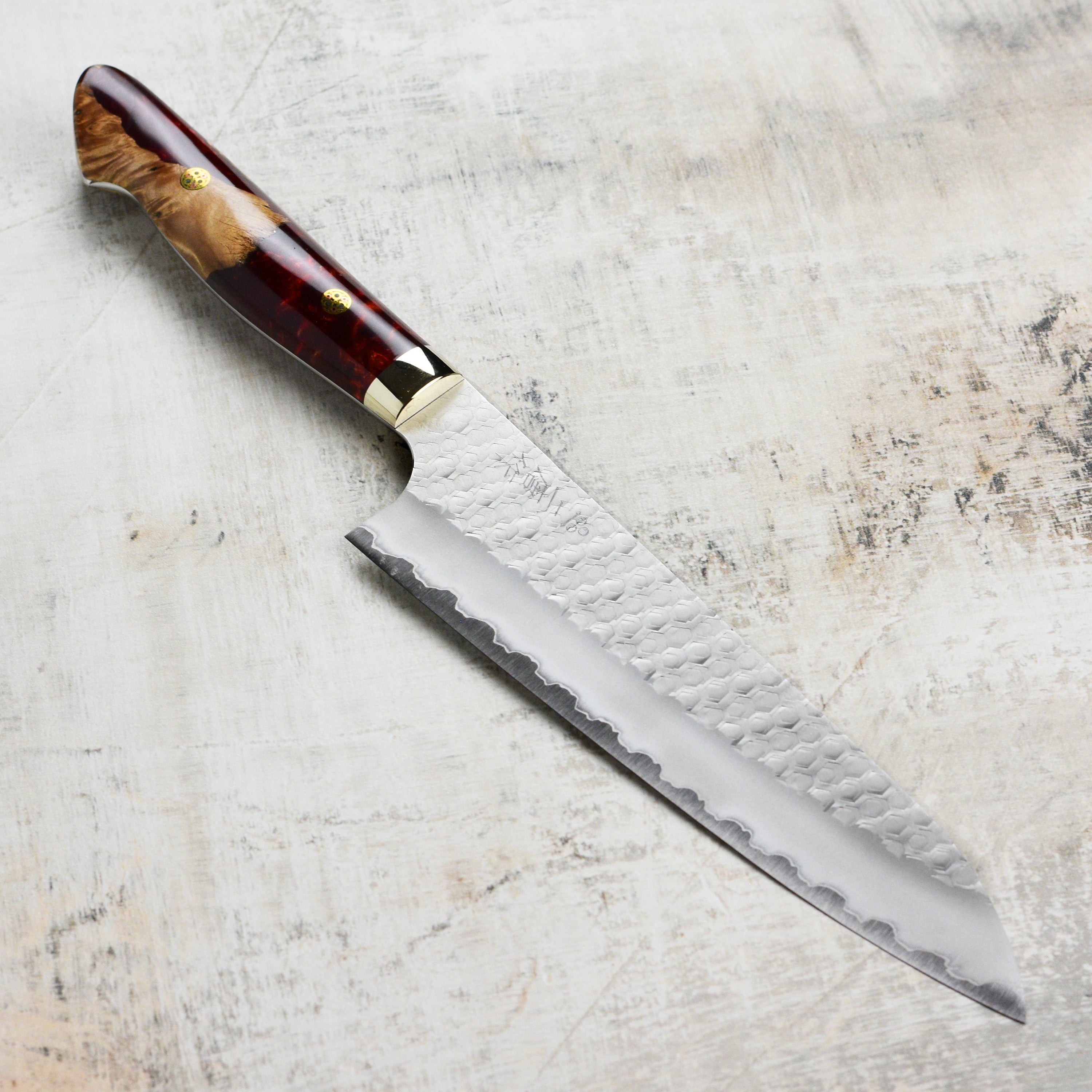 Crimson Edge SG2 hand-forged gyuto knife with acrylic handle, showing side angle for detailed view.