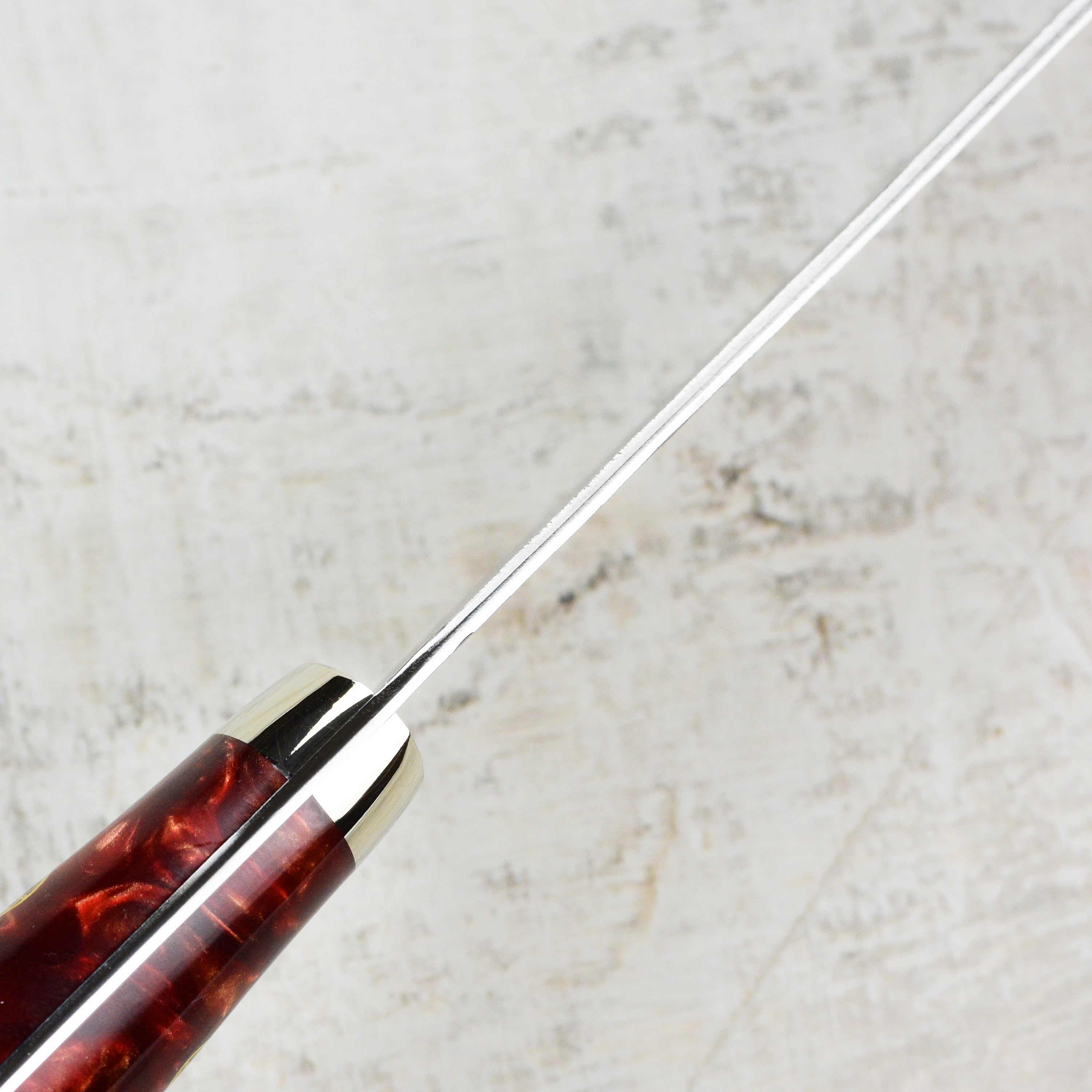 Crimson Edge Gyuto knife in use, demonstrating its performance on vegetables and meats in a professional kitchen.