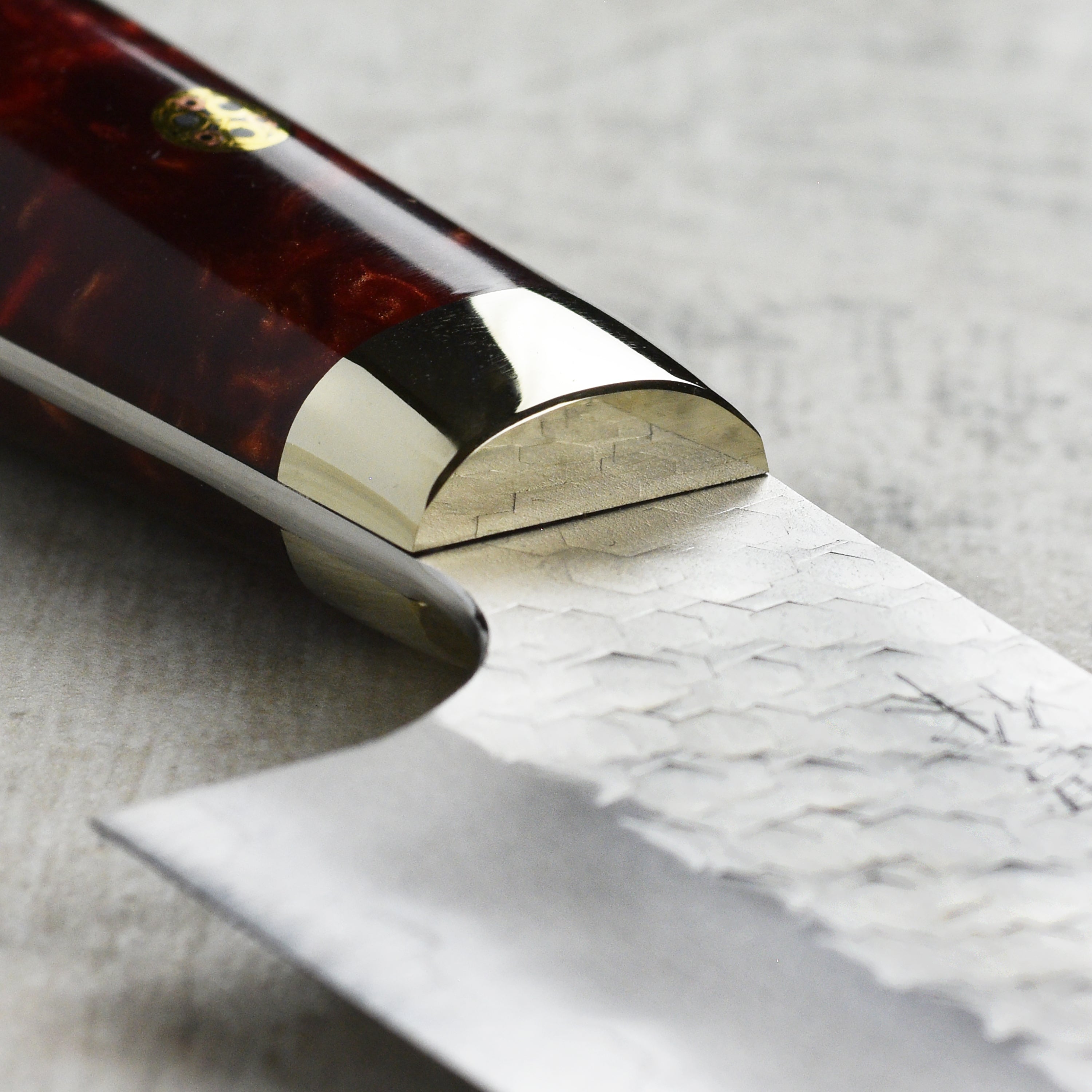 Crimson Edge SG2 hand-forged gyuto knife with acrylic handle, showing side angle for detailed view.