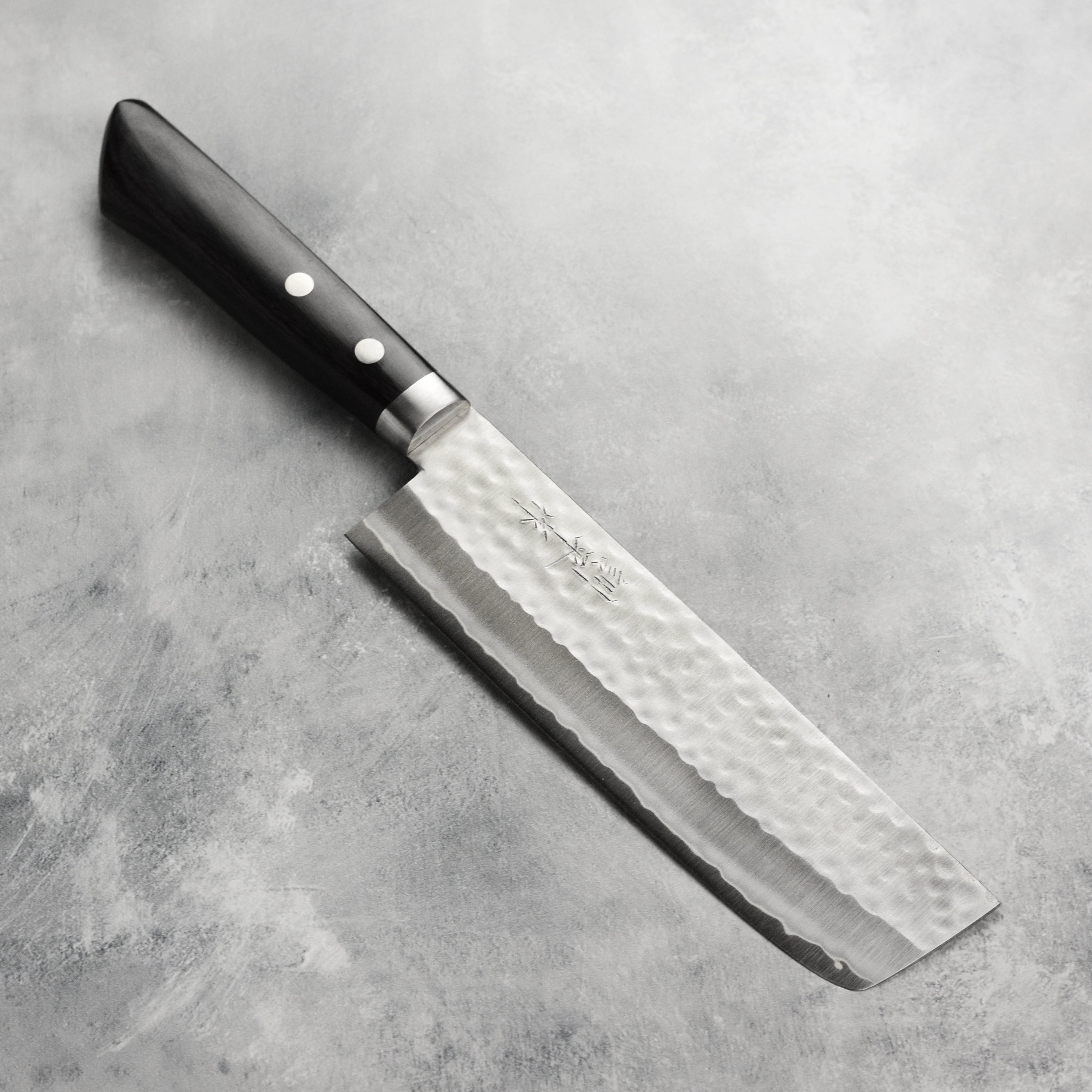 Masutani VG1 nakiri knife with hammered finish and black handle, showcasing the craftsmanship.