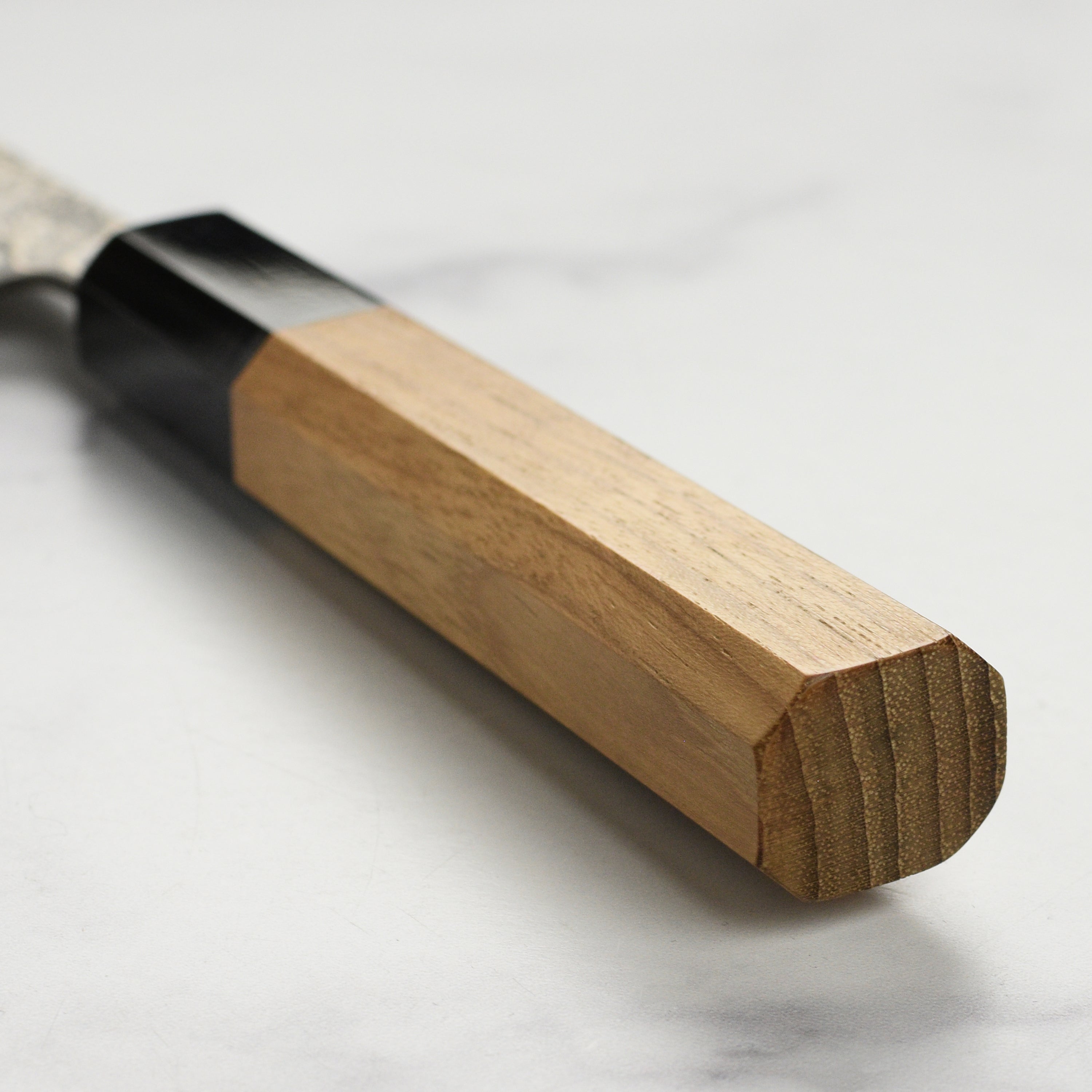 Shiro Kamo Santoku knife in action, expertly slicing vegetables on a cutting board.